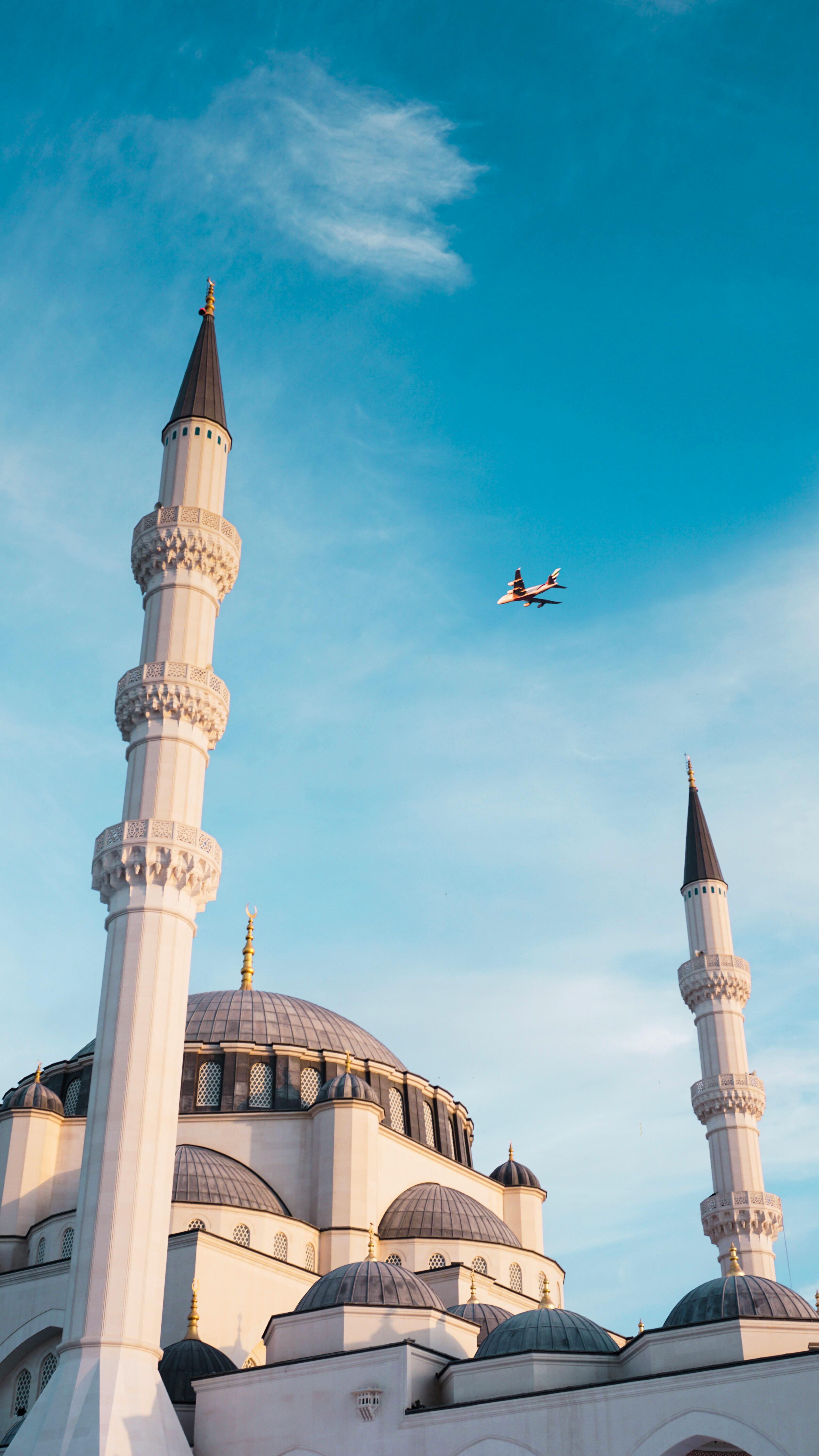 Airplane Flying Over a Mosque Building