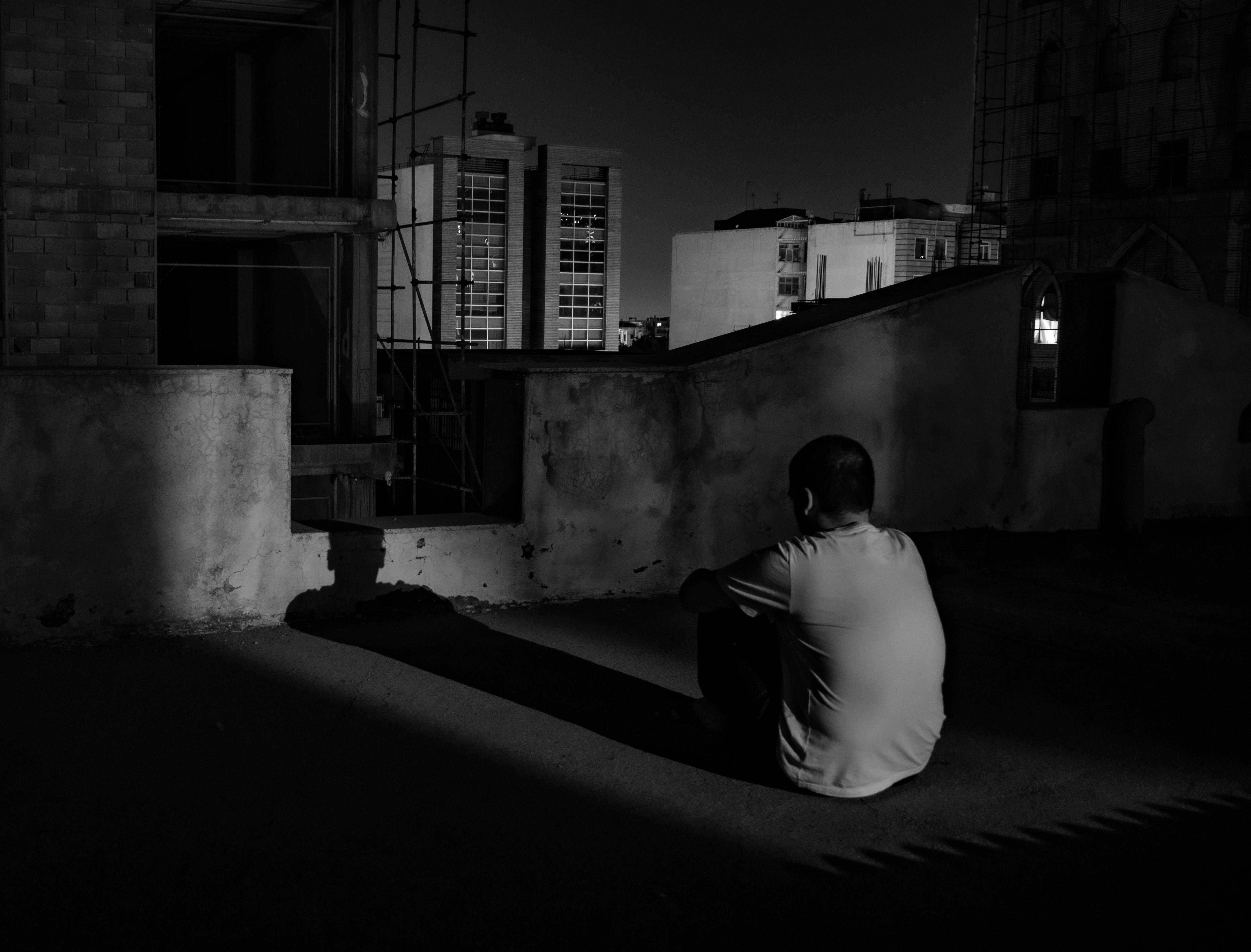 Lonely man sitting on rooftop at night