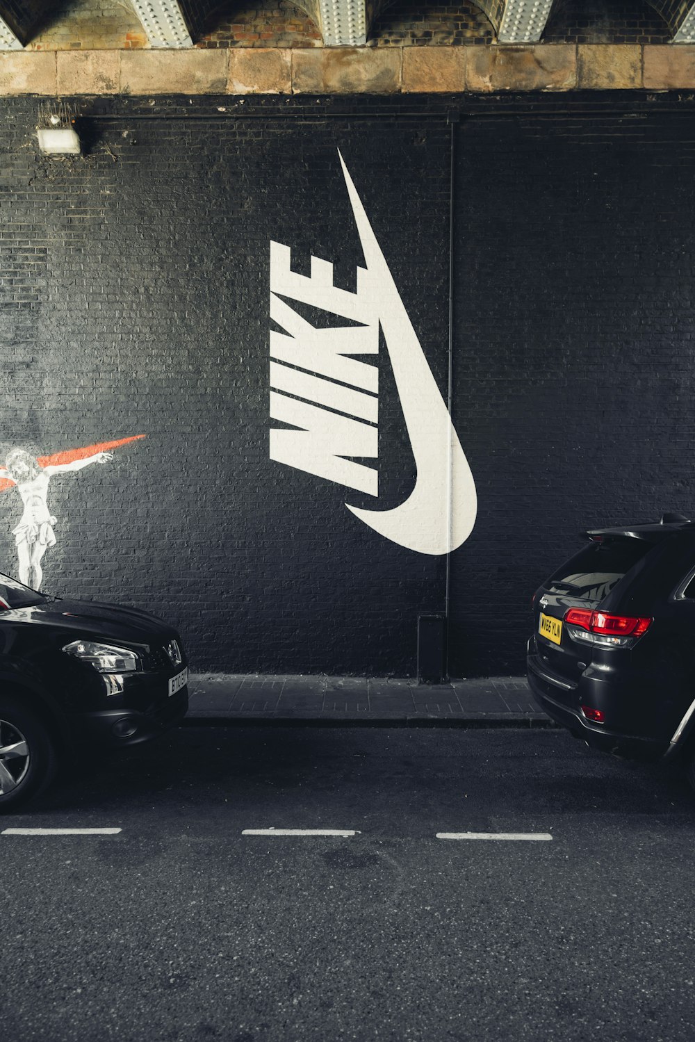 Parked vehicles beside Nike wall photo
