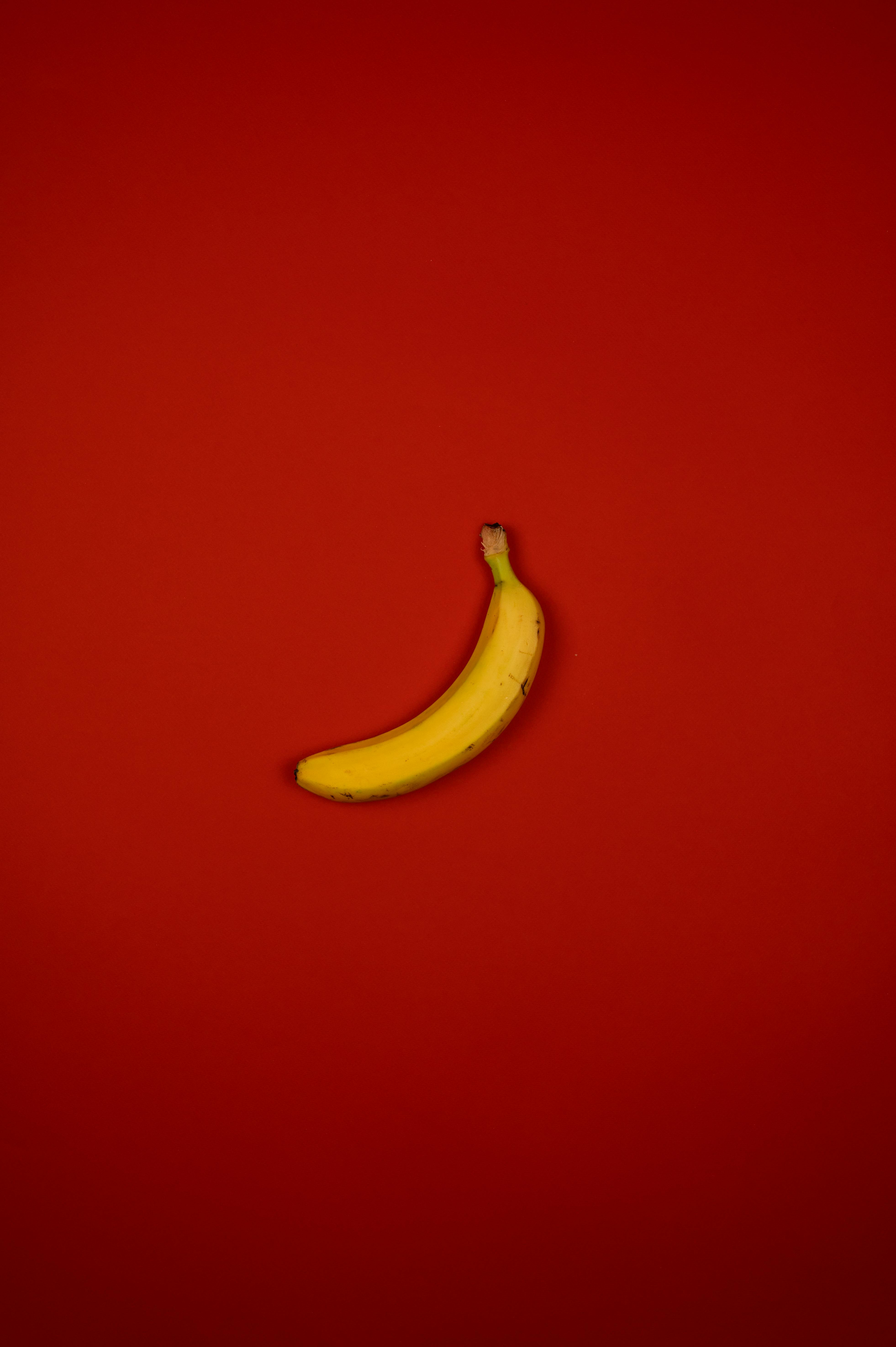 Ripe banana with stem on red background