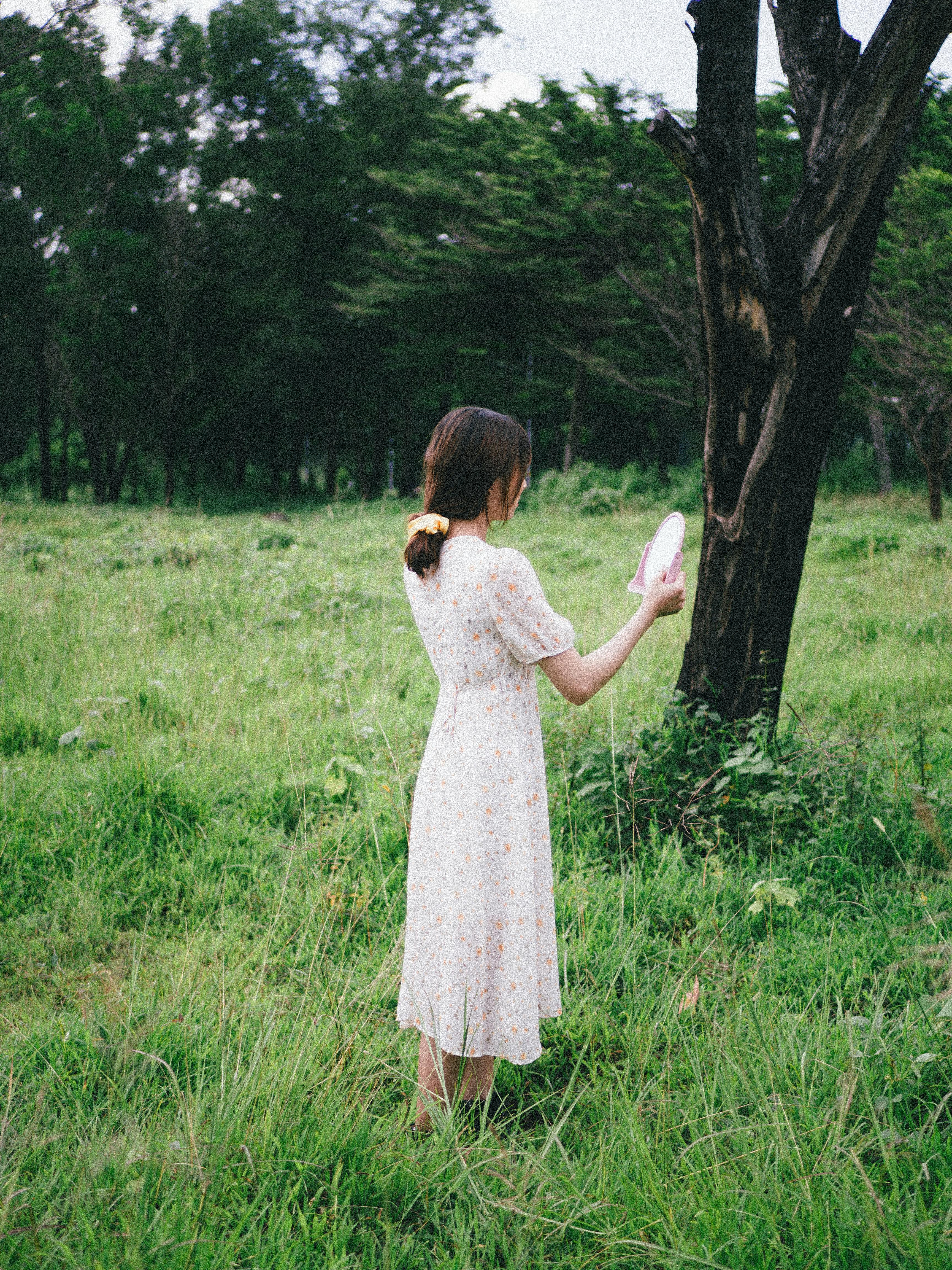 Faceless woman with mirror in field