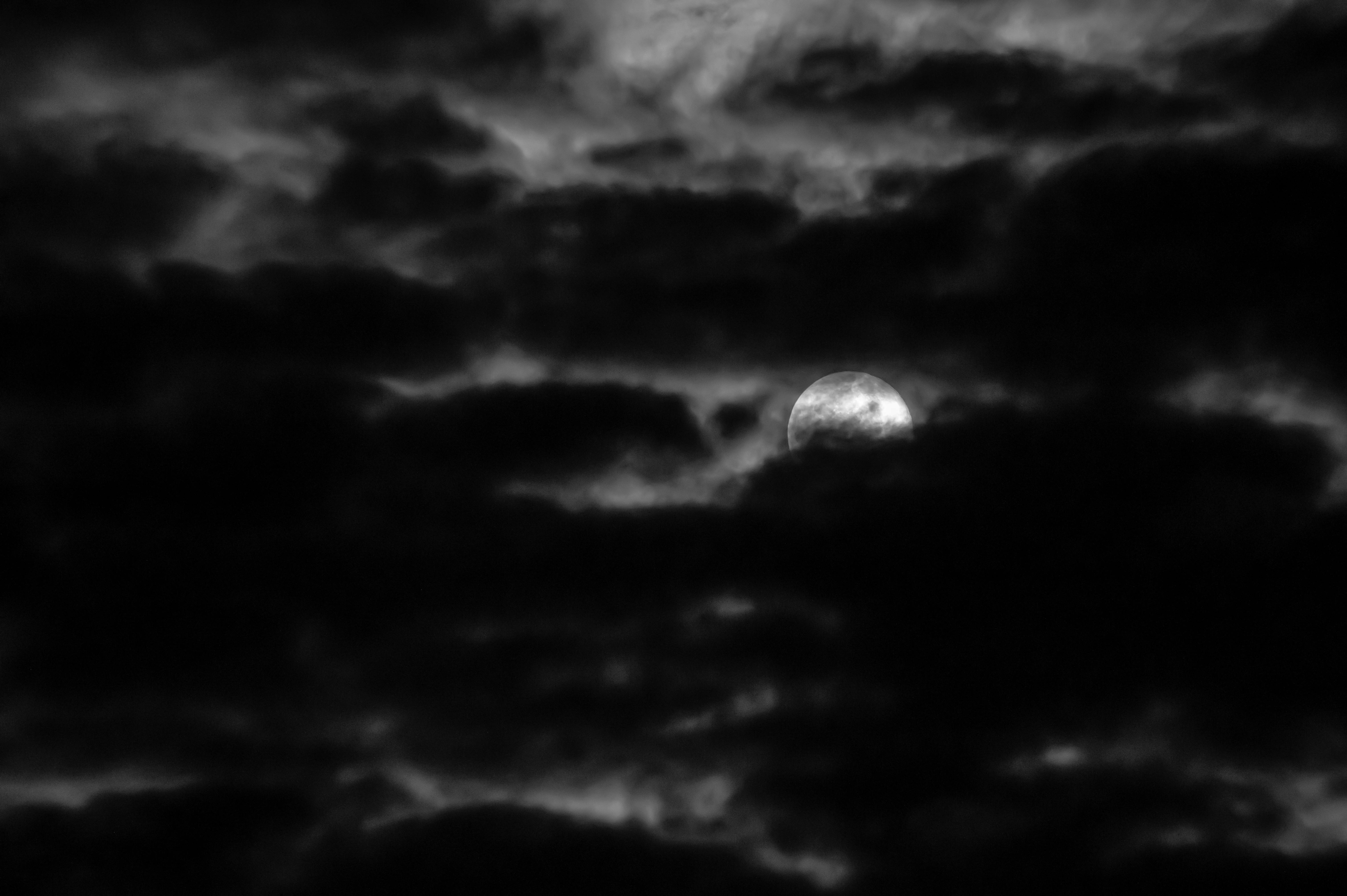 Moon shining through dark cloudy sky