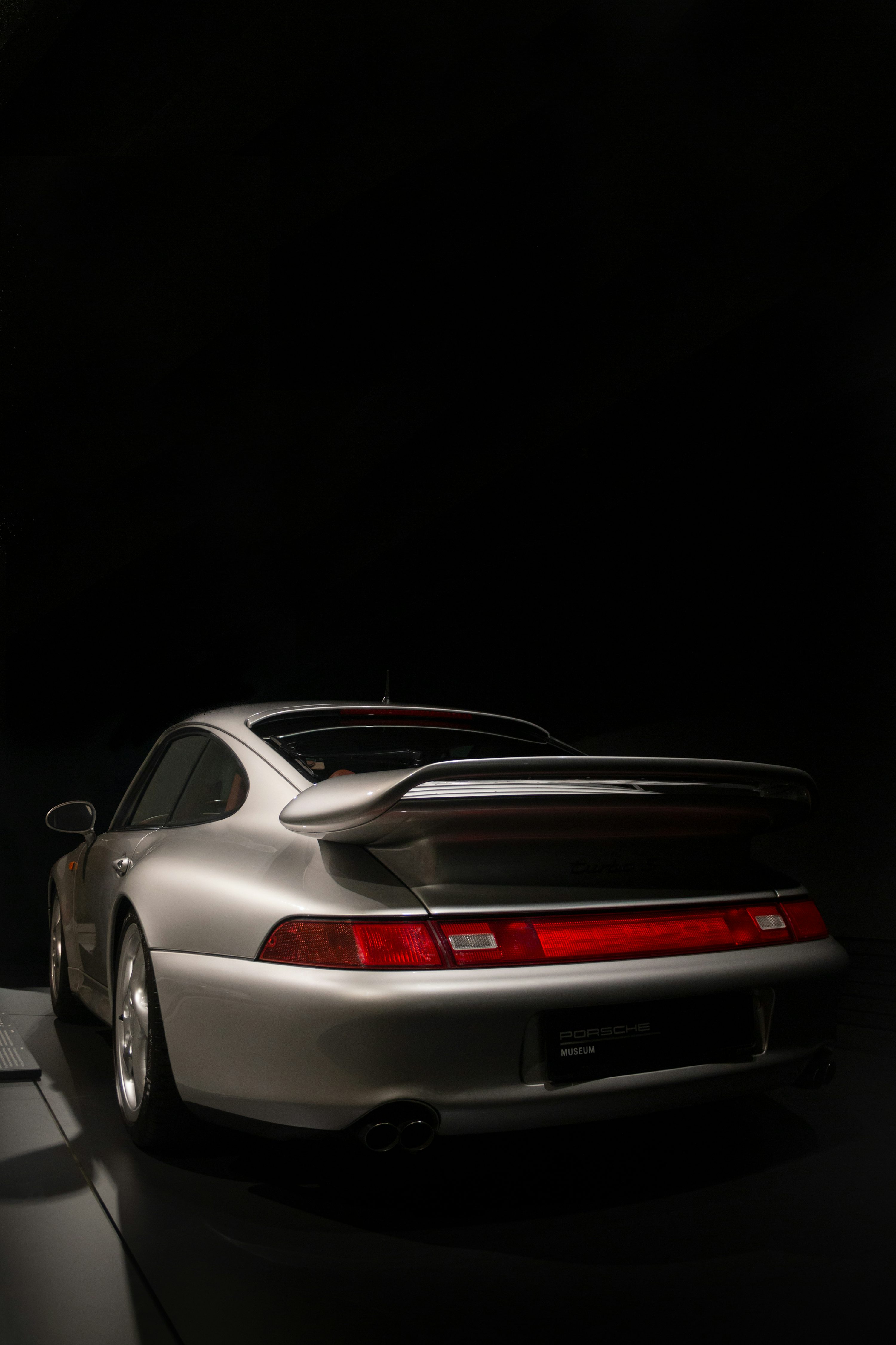 A white porsche parked in a dark room