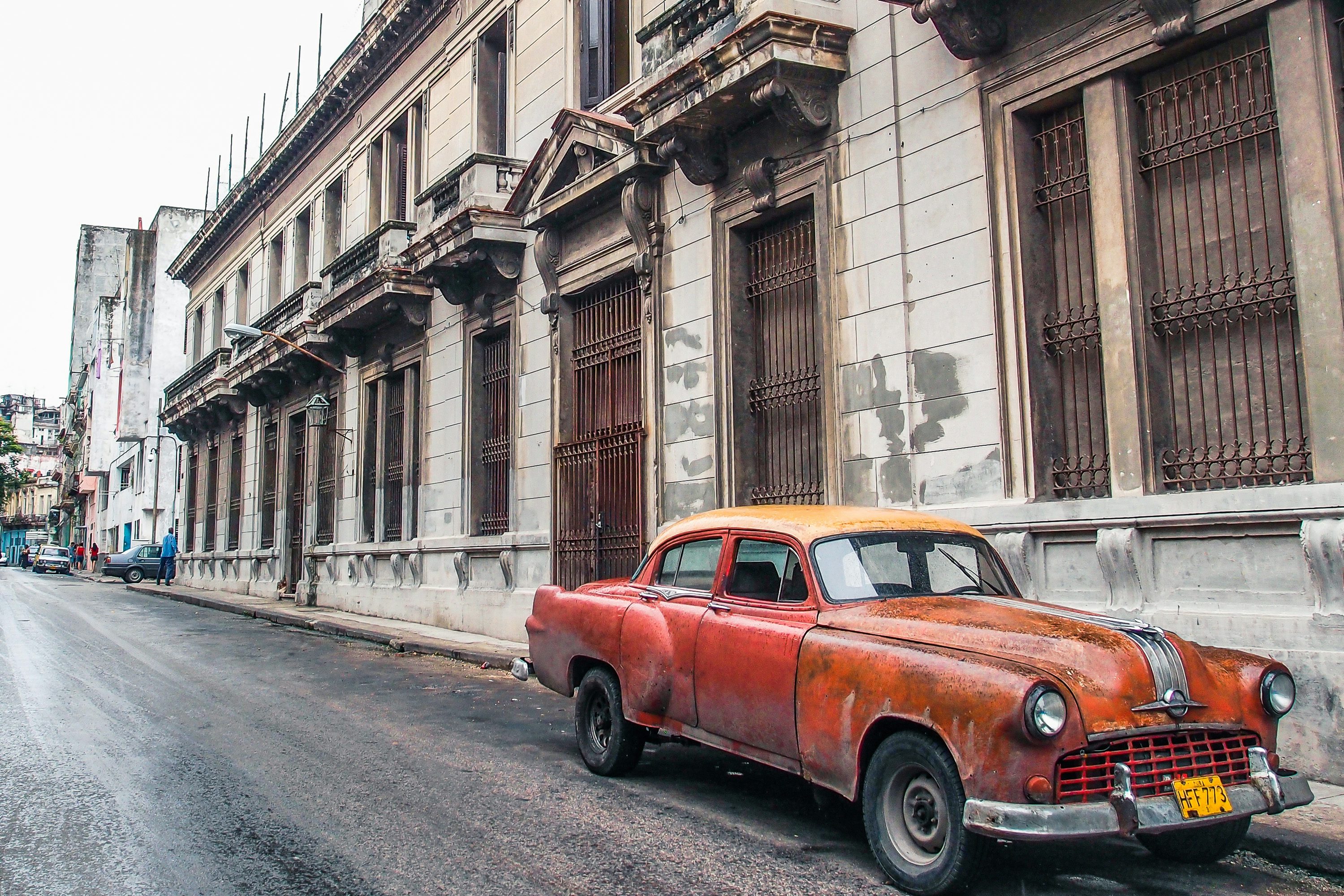 An old orange car parked on the side