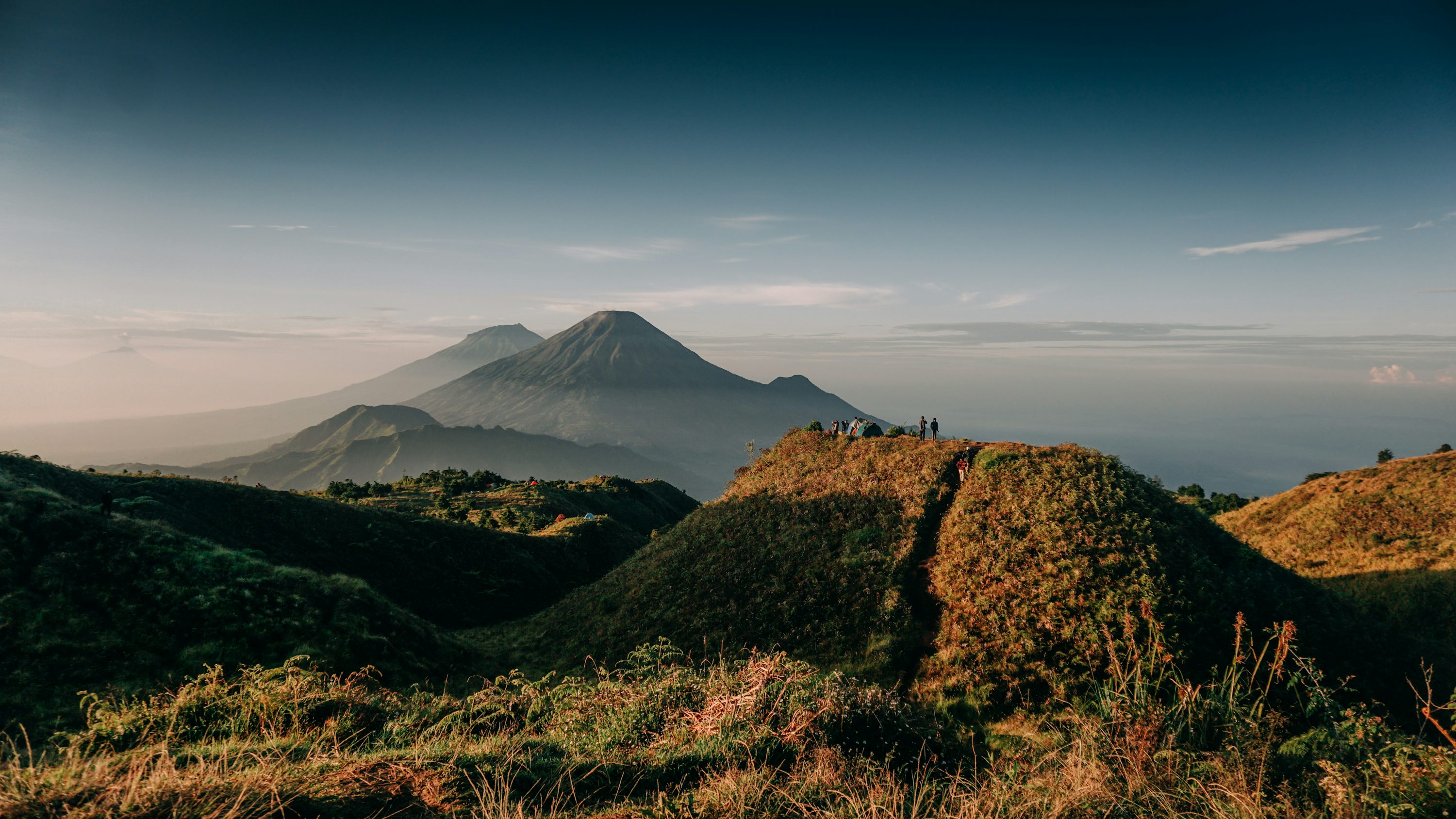 A view of a mountain with clouds in