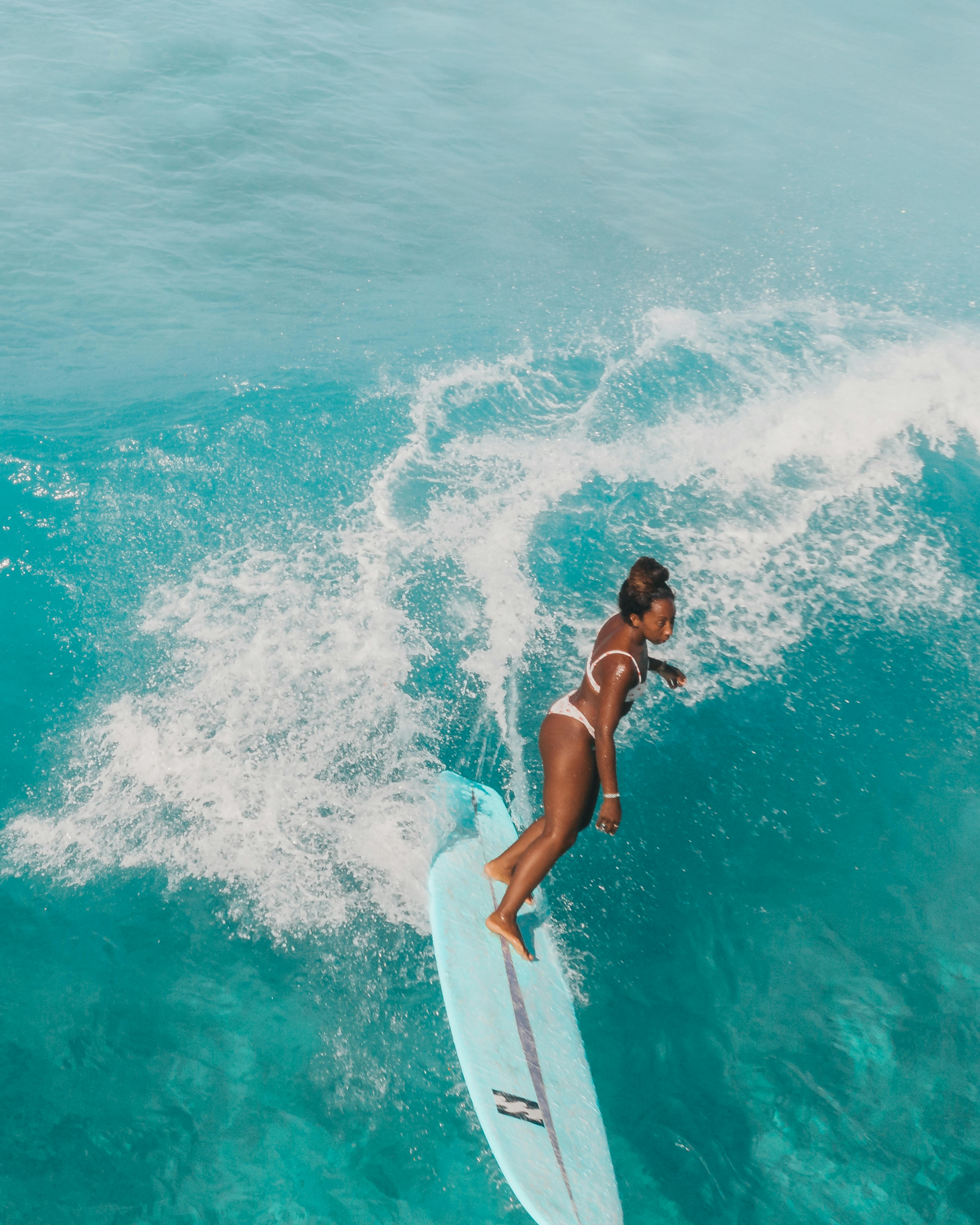 Woman in Black Bikini Sitting on White Surfboard on Blue Sea · Free