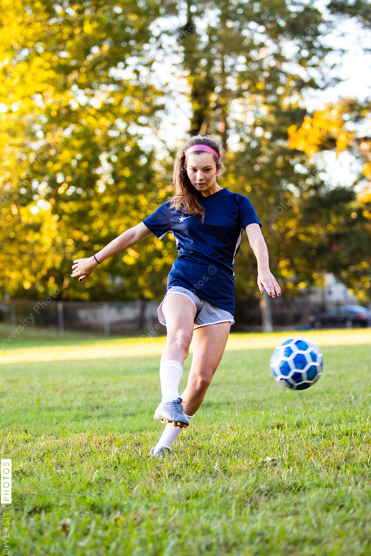 Teen girl soccer player kicking ball