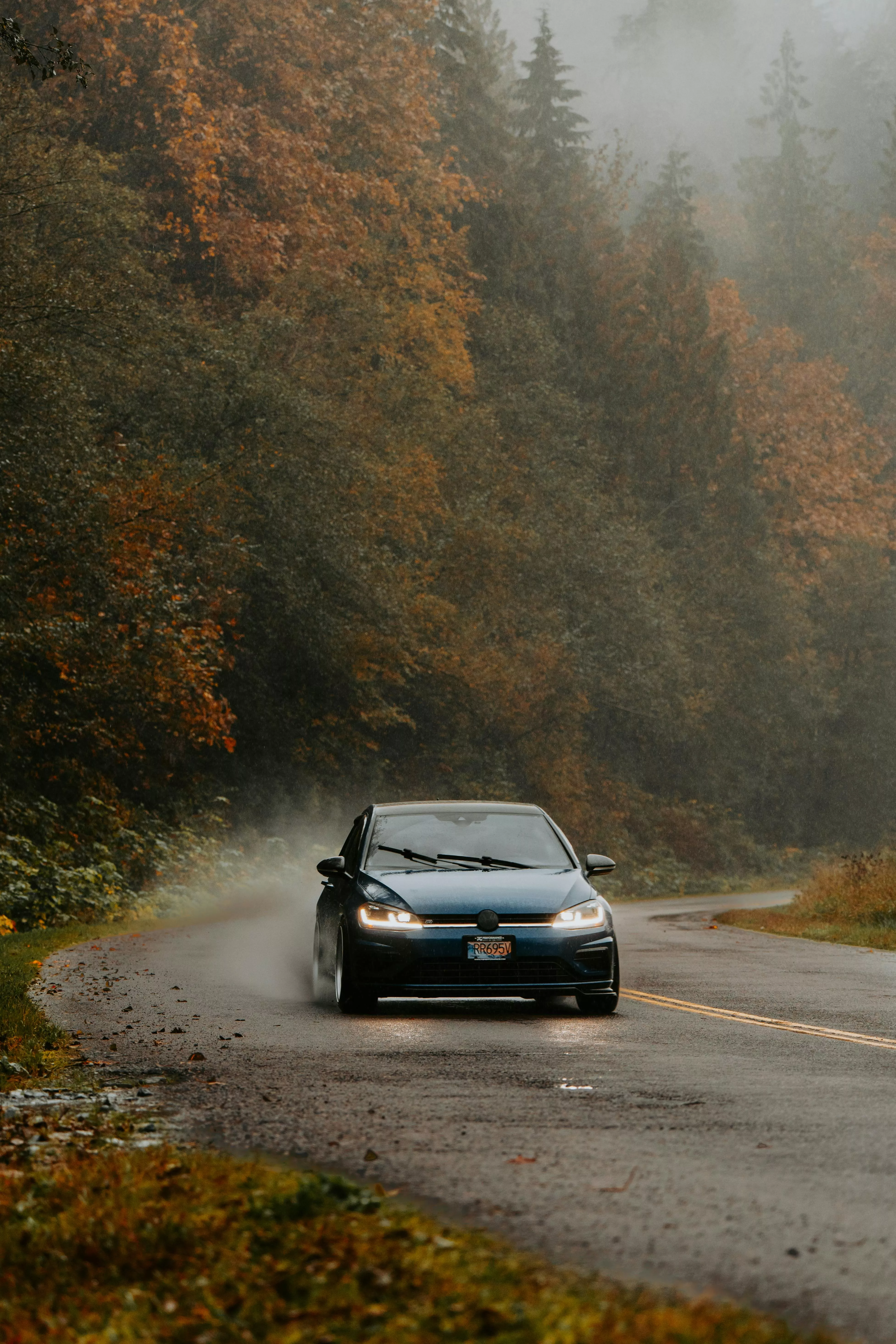 Car driving through foggy autumn forest