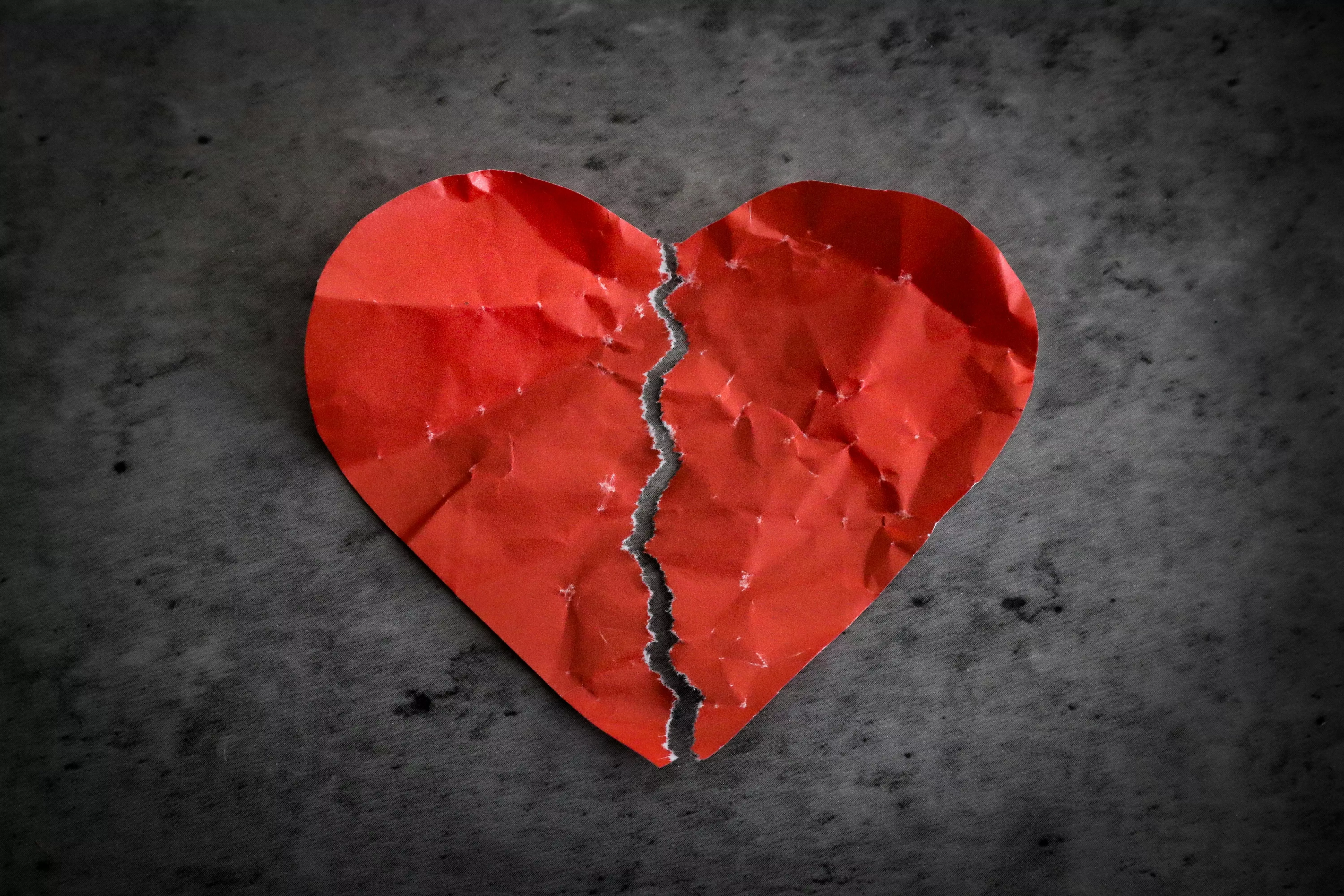 Red paper heart ripped in half on dark