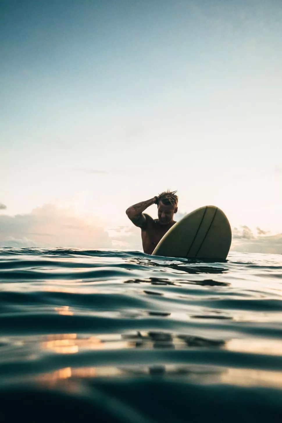 Surfer contemplating ocean at sunset