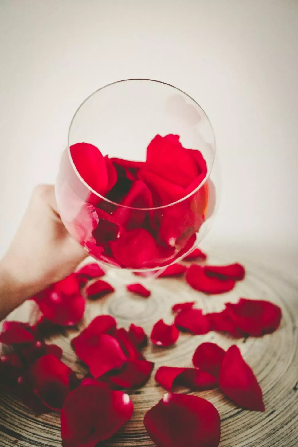 Woman hand and rose petals with glass