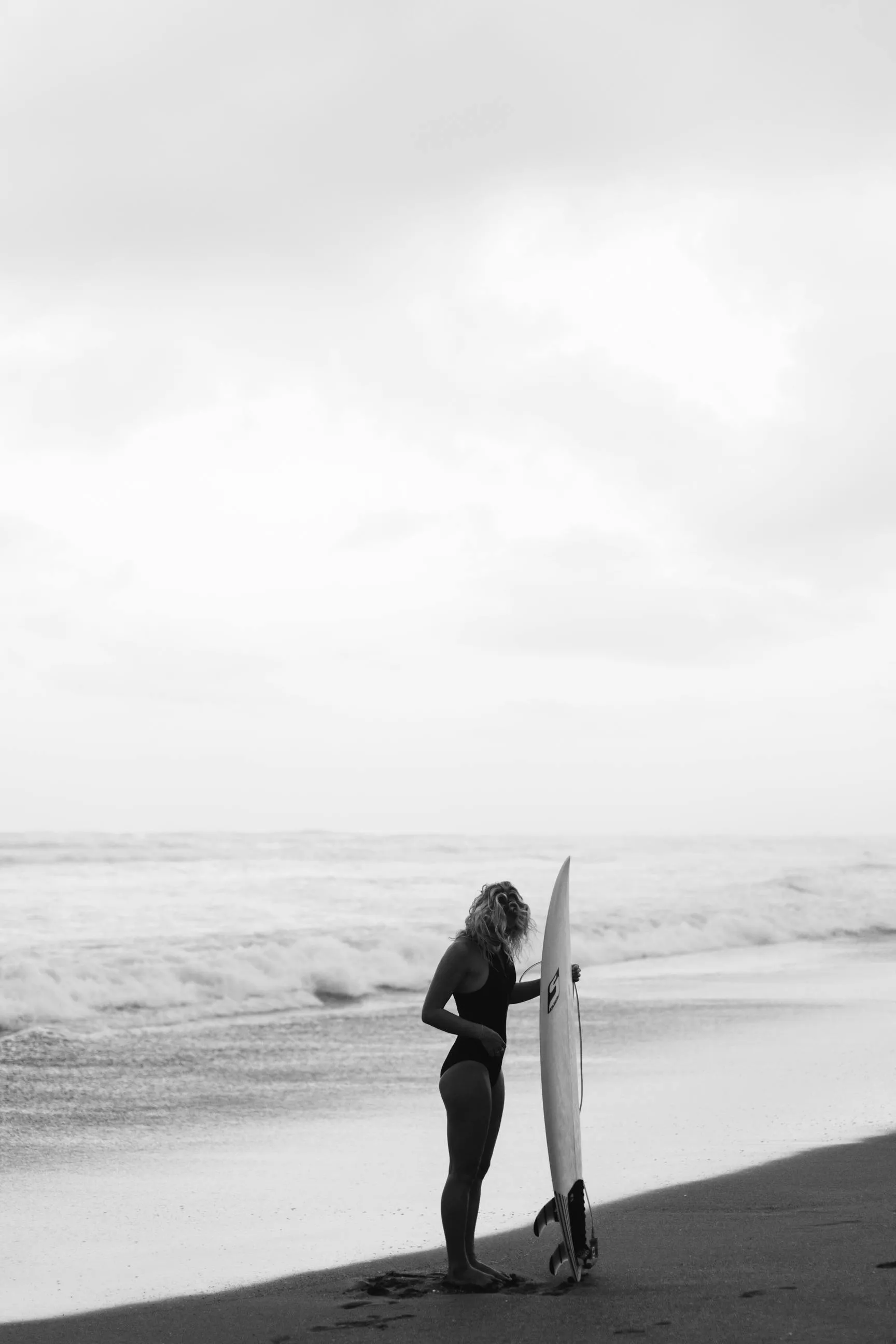 Woman Standing on a Beach with a Surfboard · Free