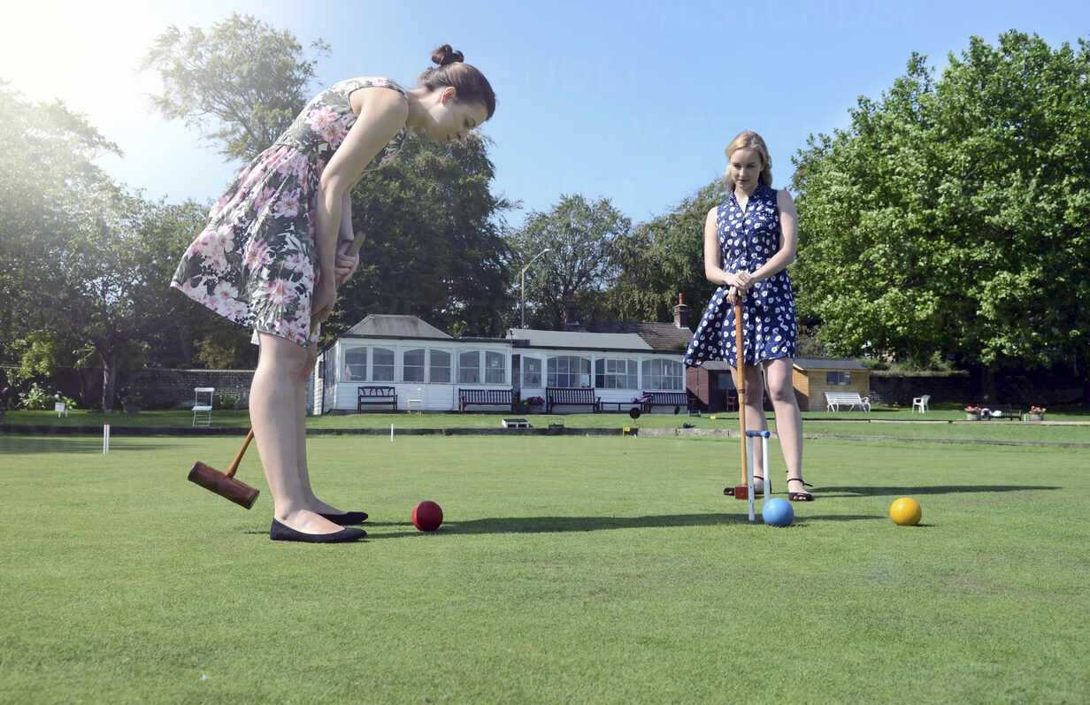 Caucasian women playing croquet on lawn