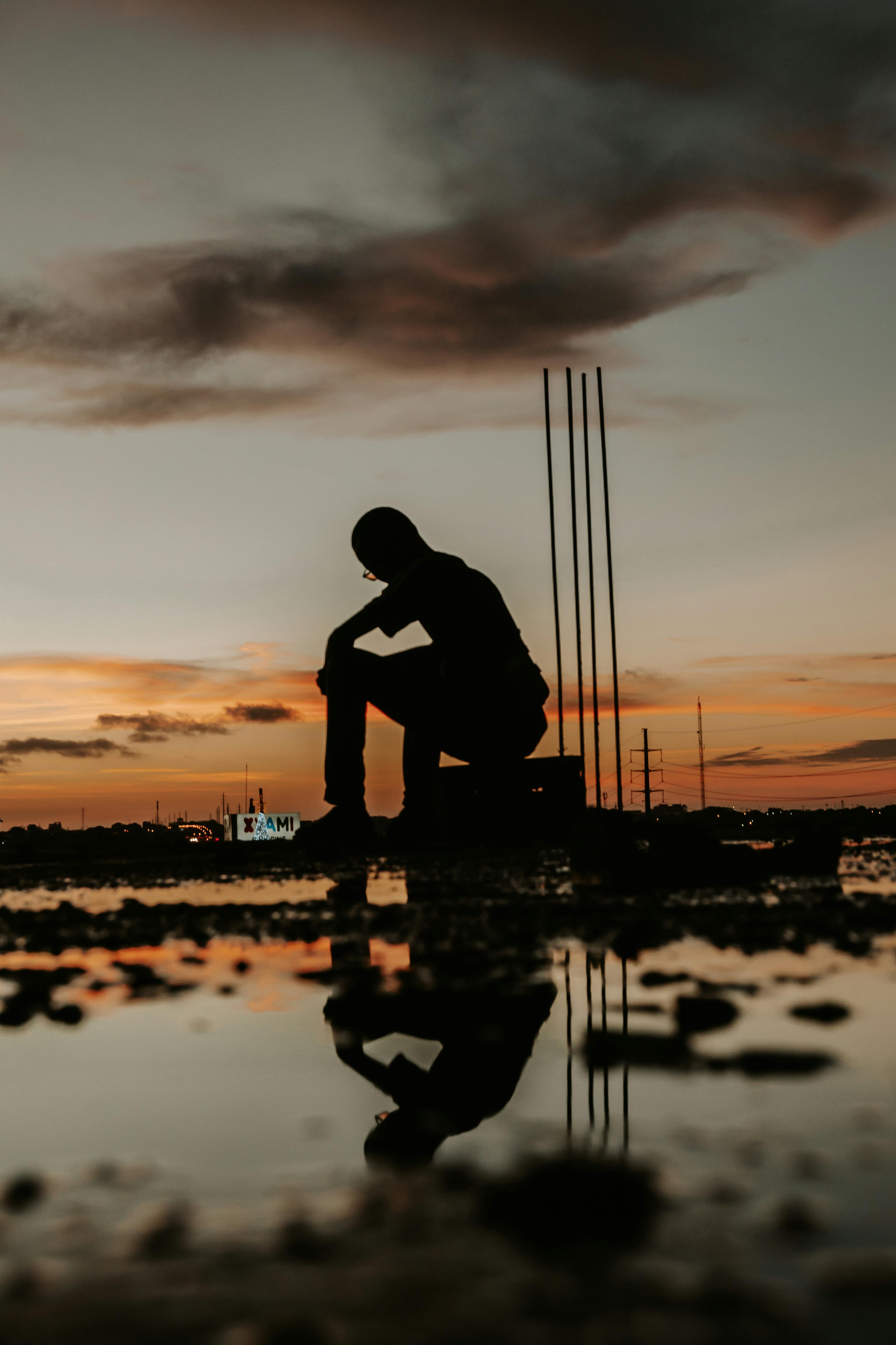 Silhouette of a Man Sitting on the Background of a Sunset · Free