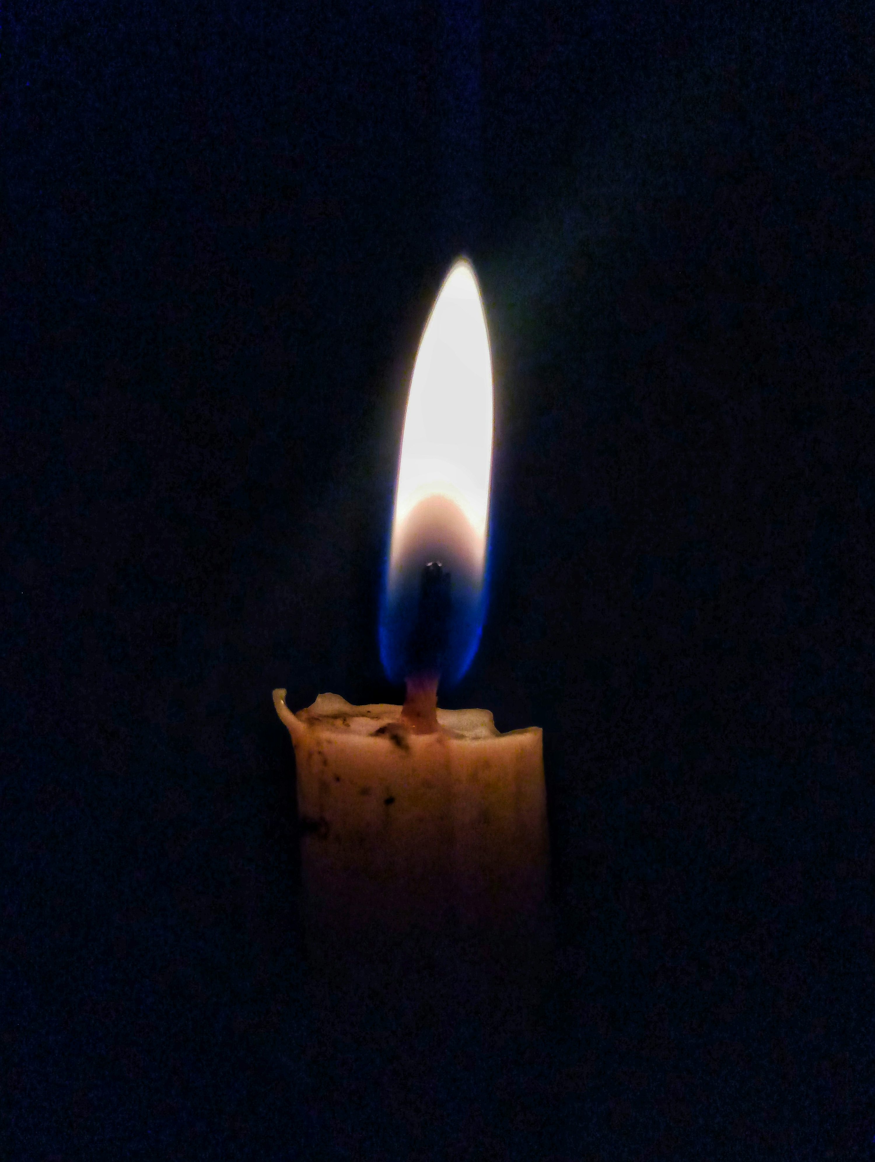 A lit candle in the dark with a dark