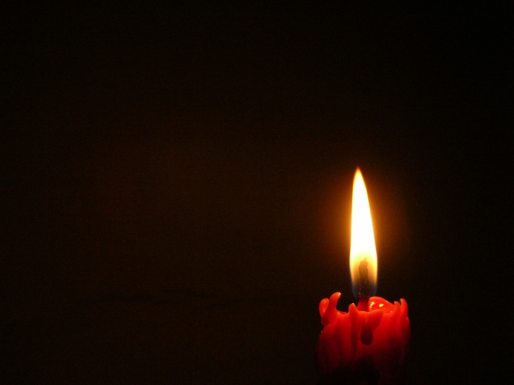 Burning candle on black background