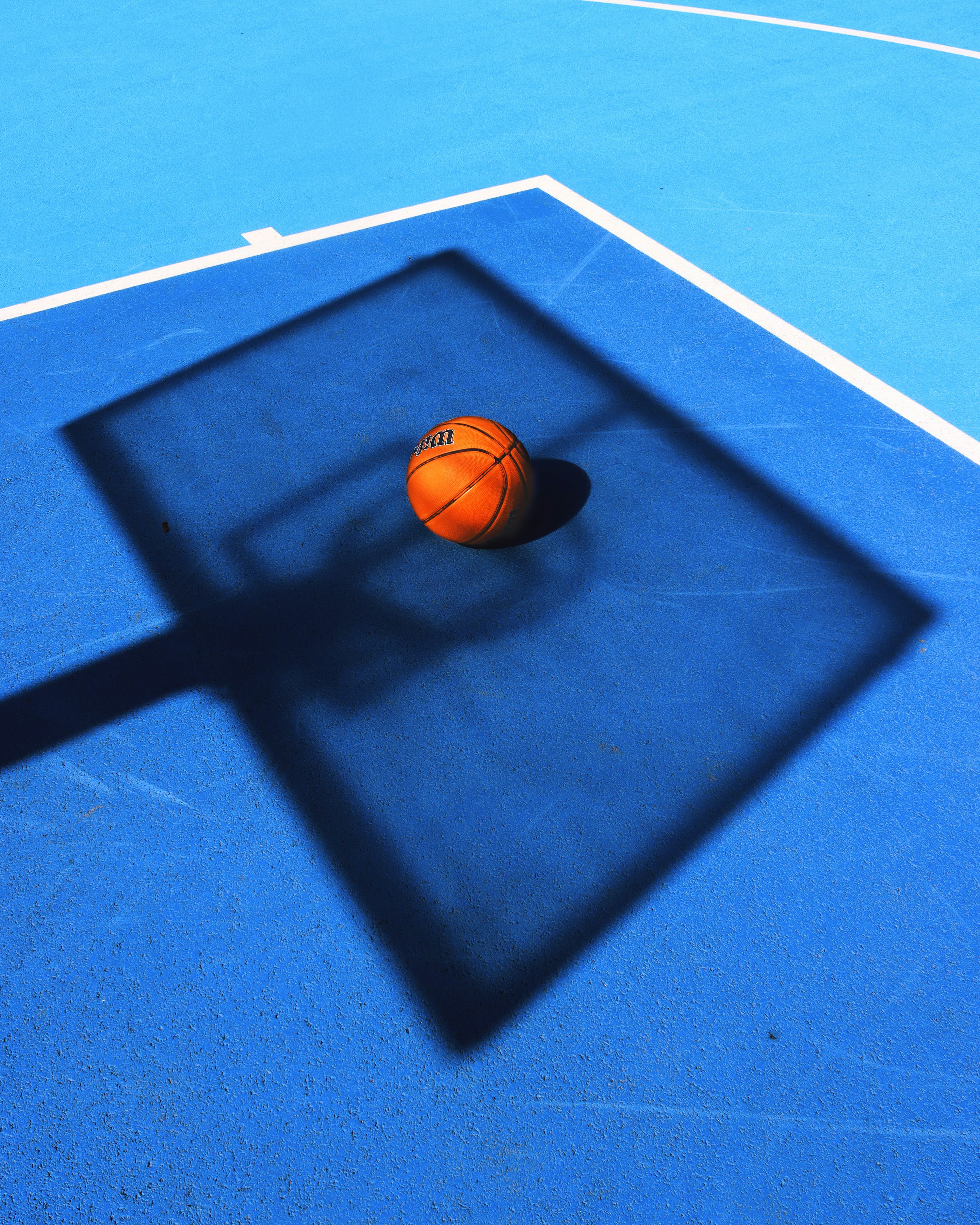 shadow of a basketball on a blue court