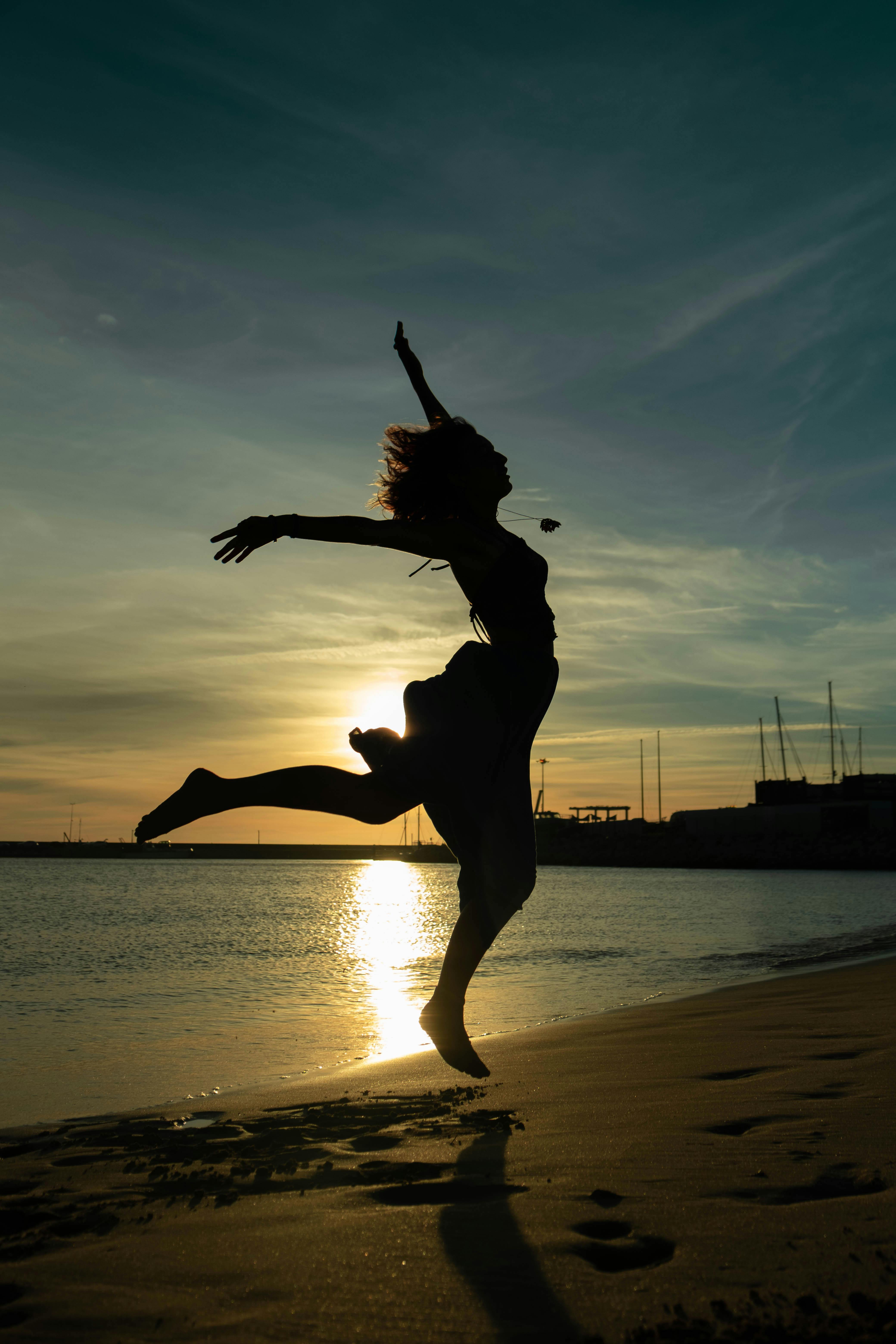Woman Jumping on Beach at Sunset