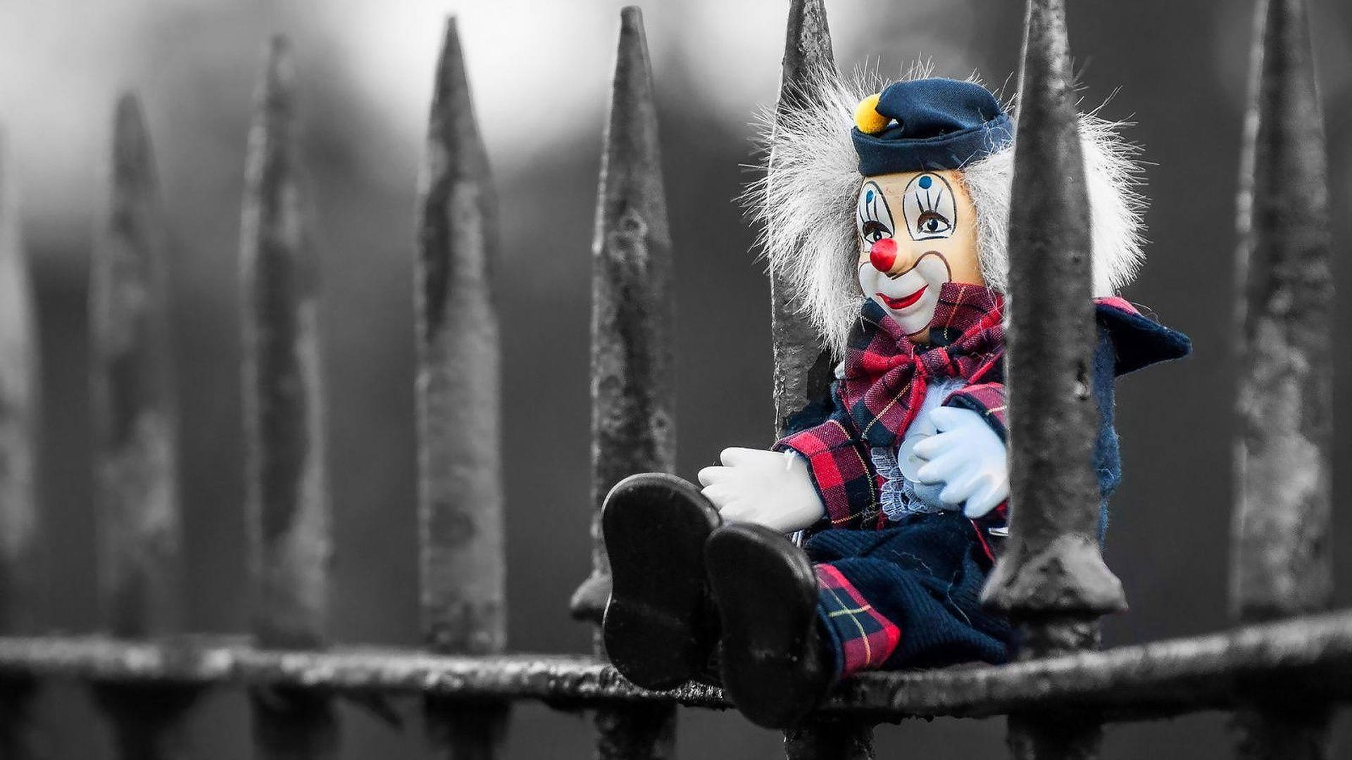 Download Clown Doll On Fence Wallpaper