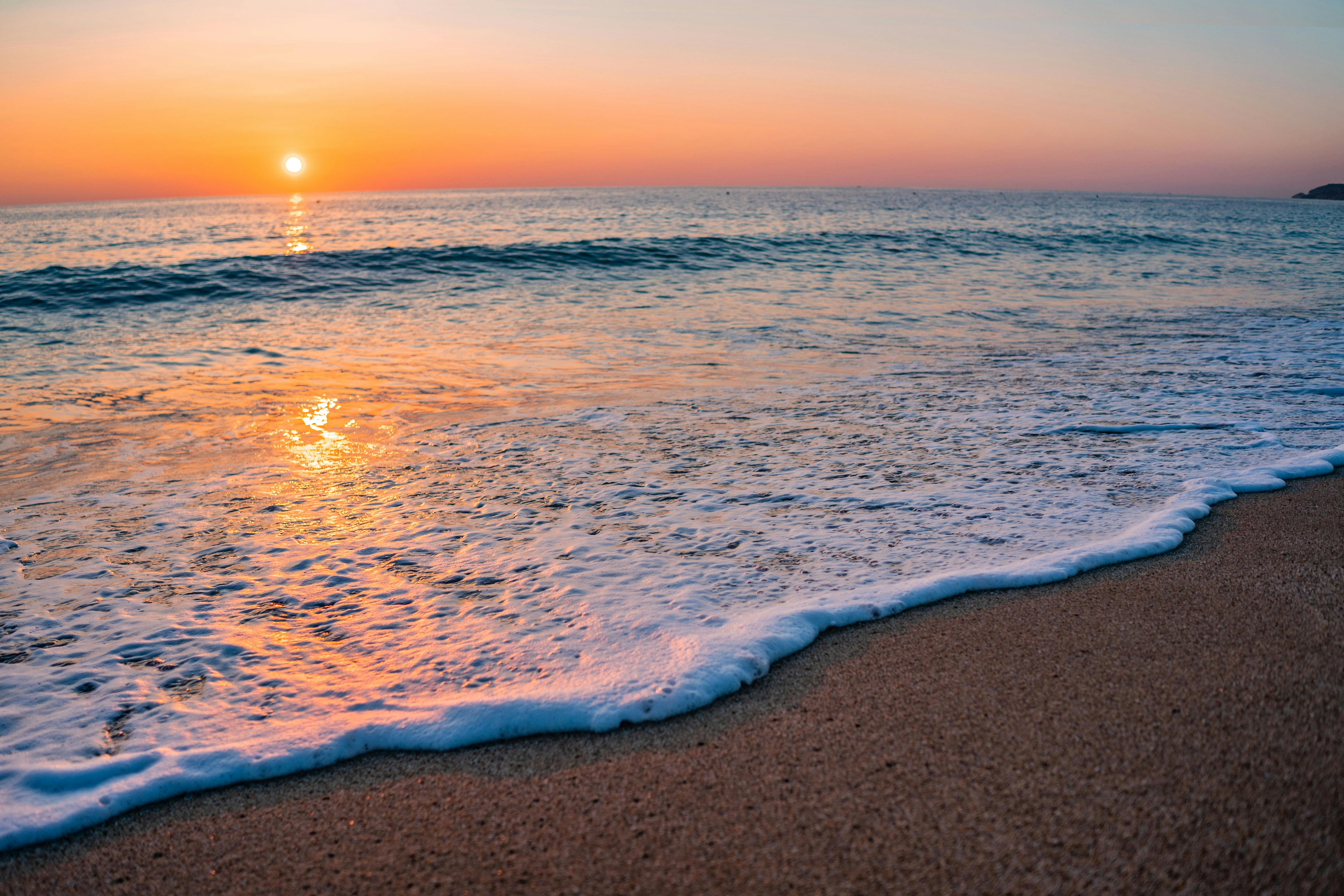 Sea Foam on a Sandy Beach at Sunset