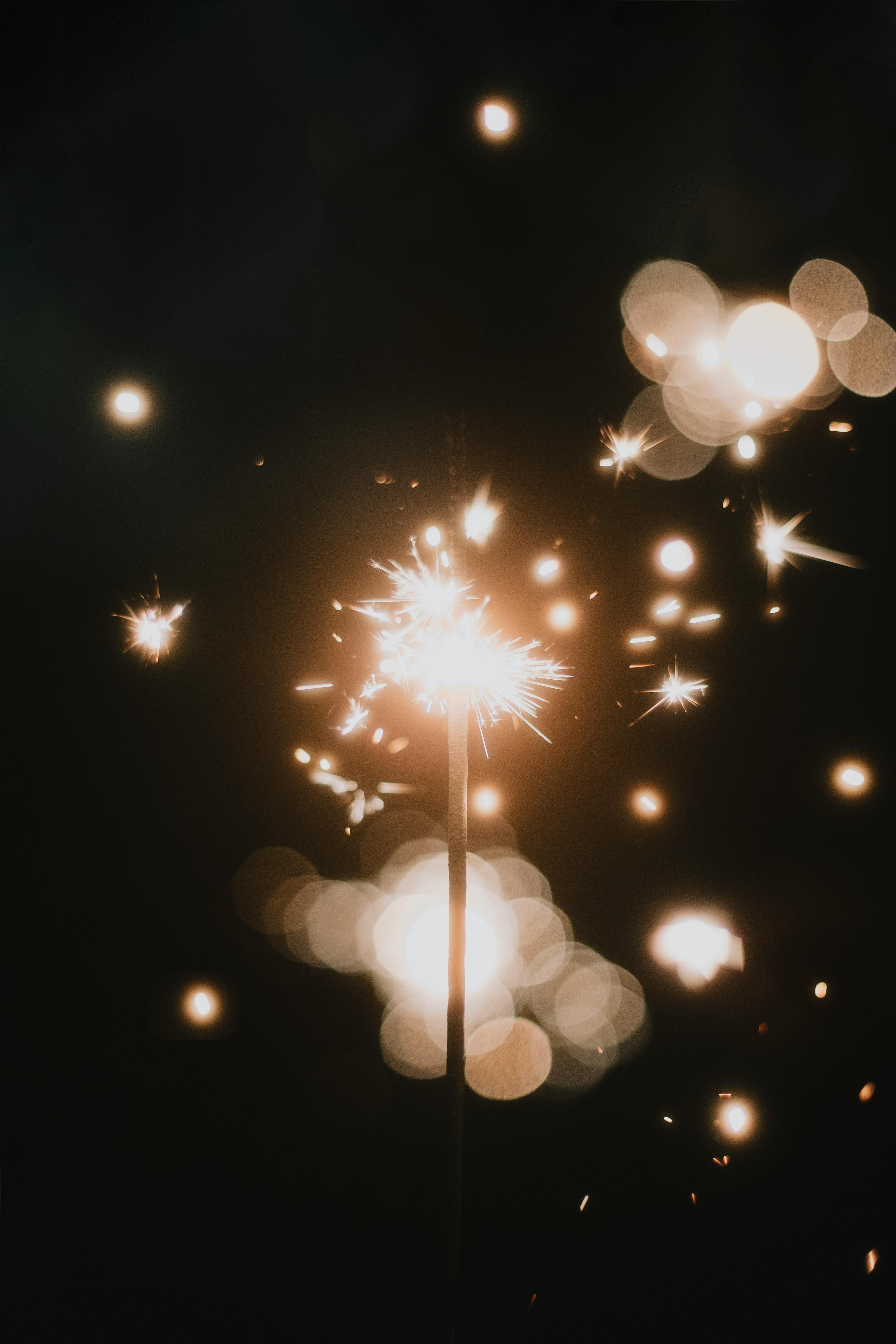 Close Up Of A Sparkler And Blurry Sparks Flying Against Dark Background · Free