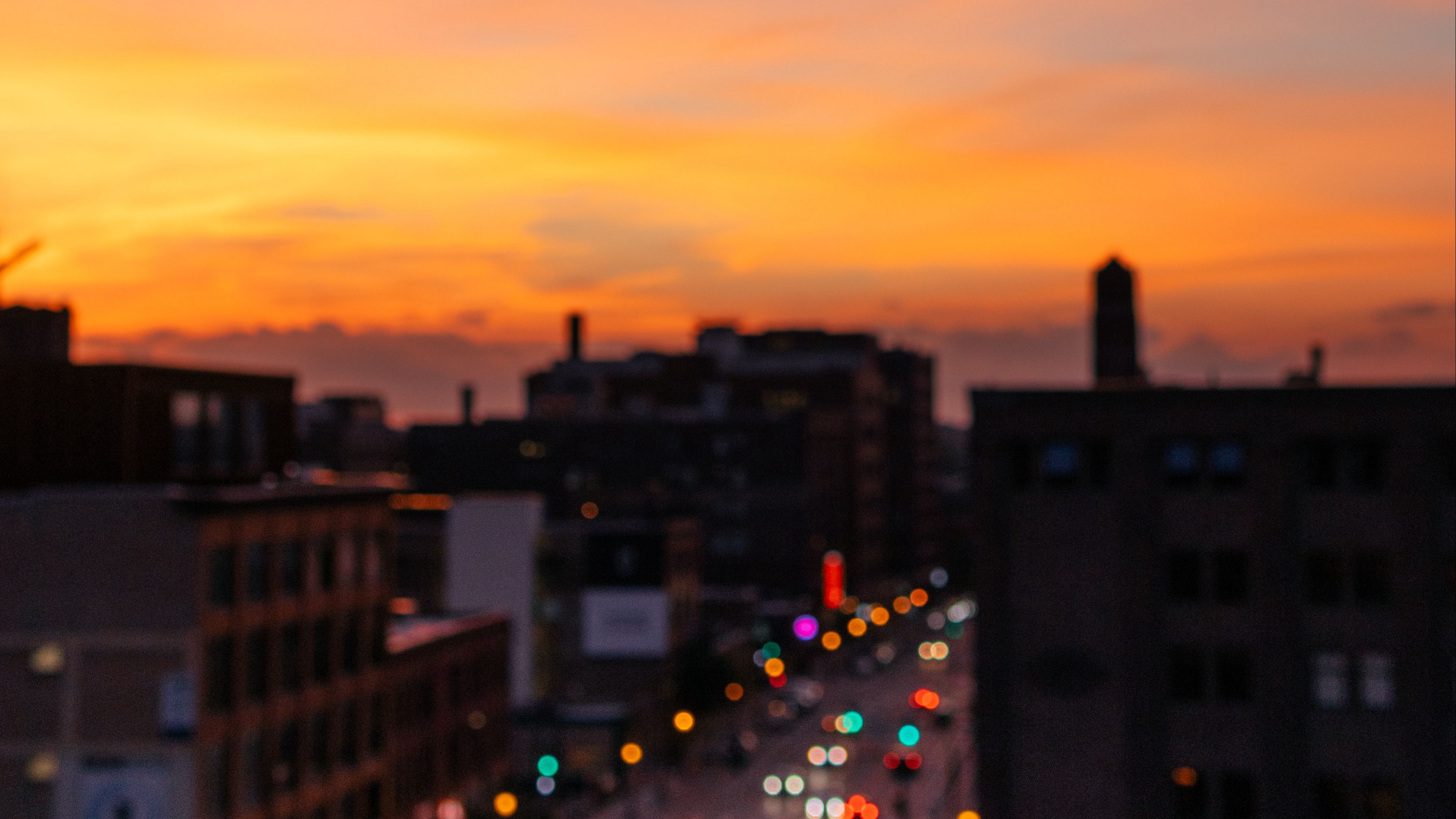 Download wallpaper 3840x2160 blur, city, glare, sunset, buildings 4k uhd 16:9 HD background