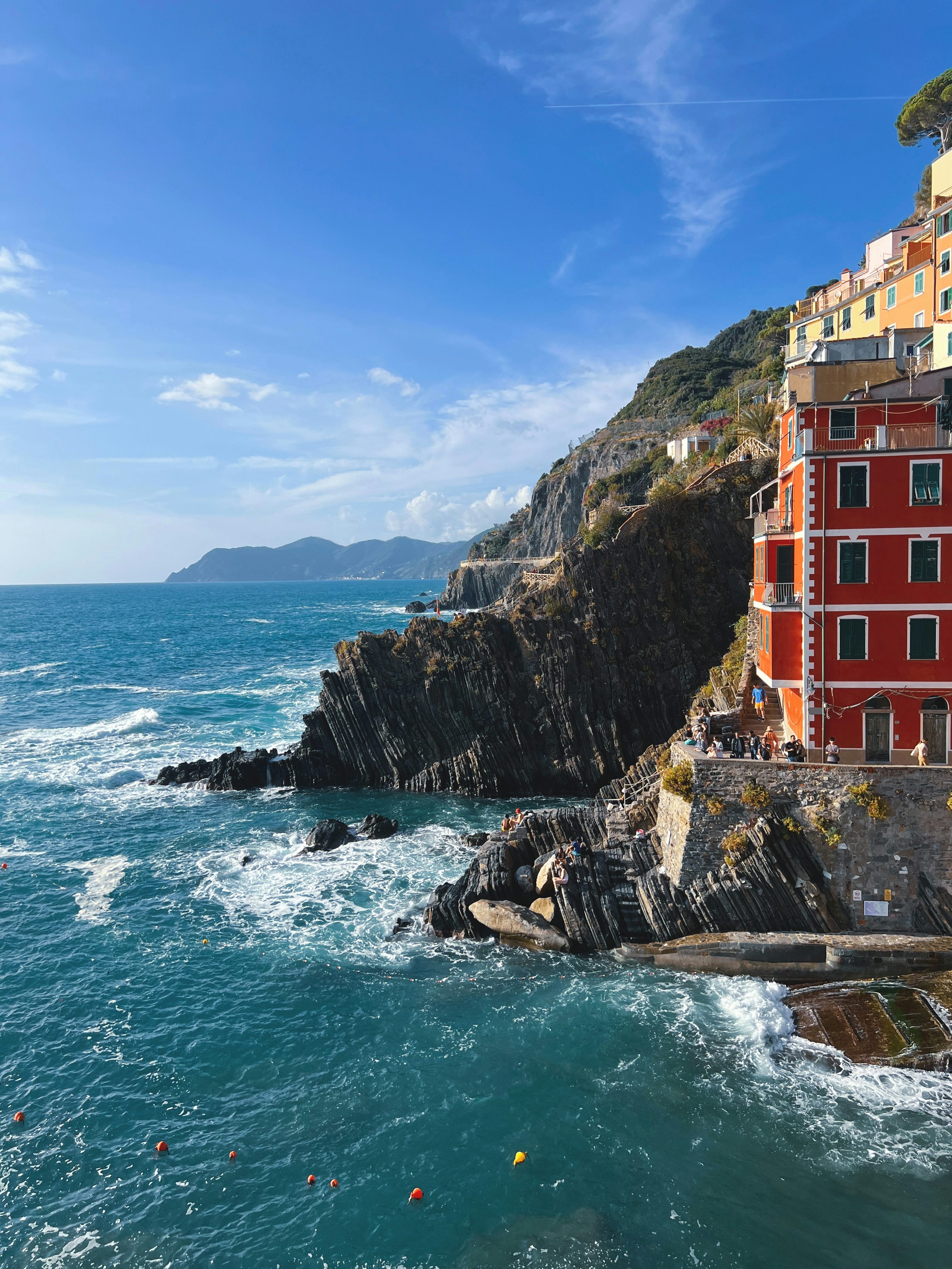 A red building on the side of a cliff next to the ocean photo