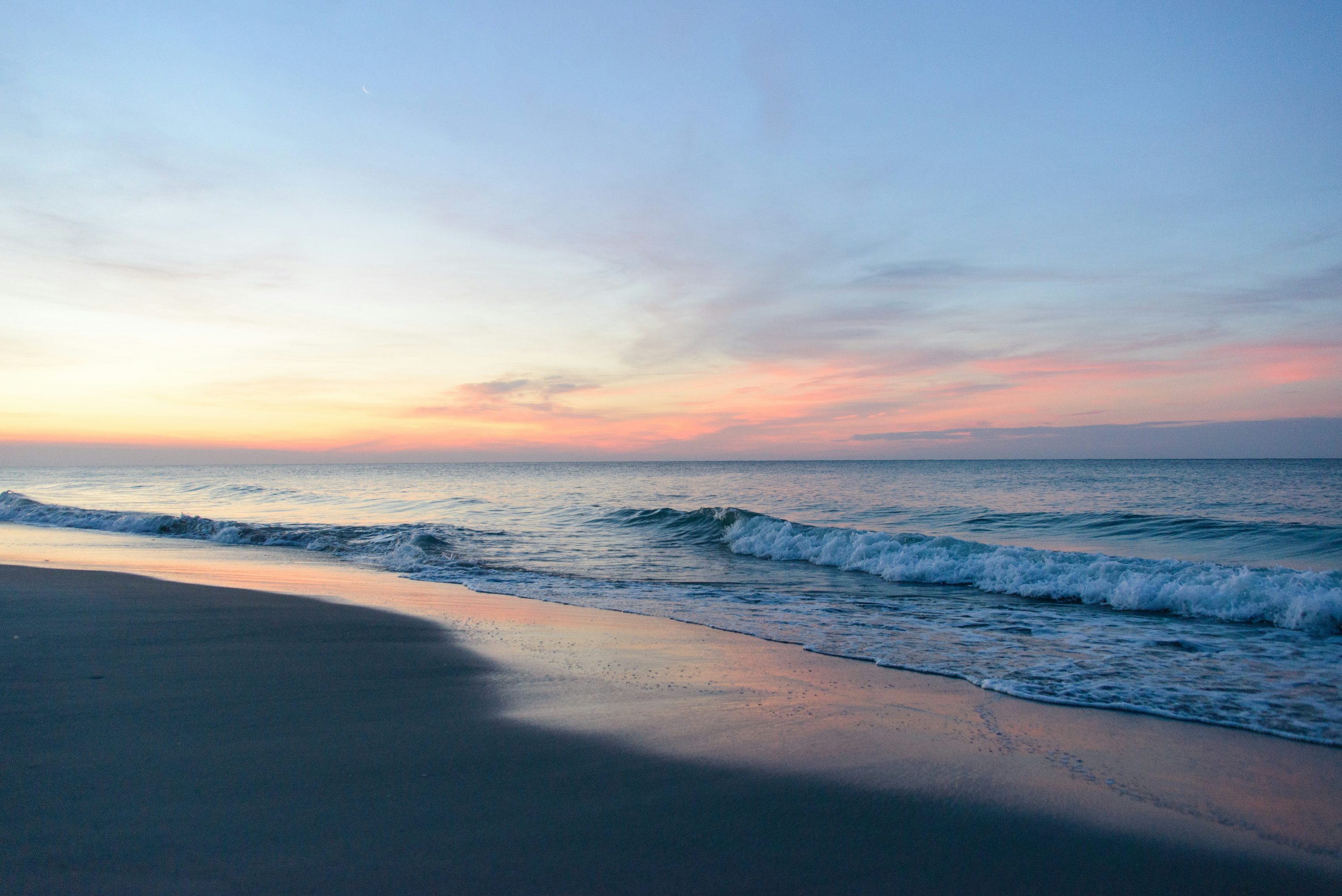 Sea waves crashing on shore during sunset photo