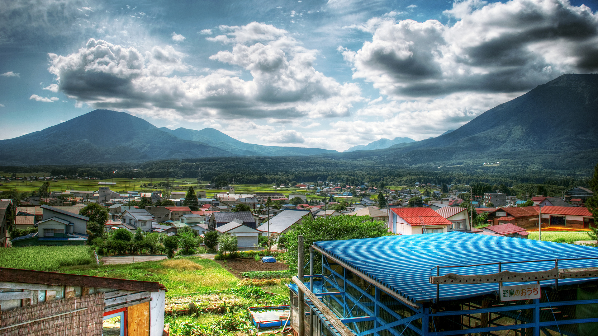 Sunny Village Landscape HD Wallpaper: Mountains, Clouds, and Community Charm