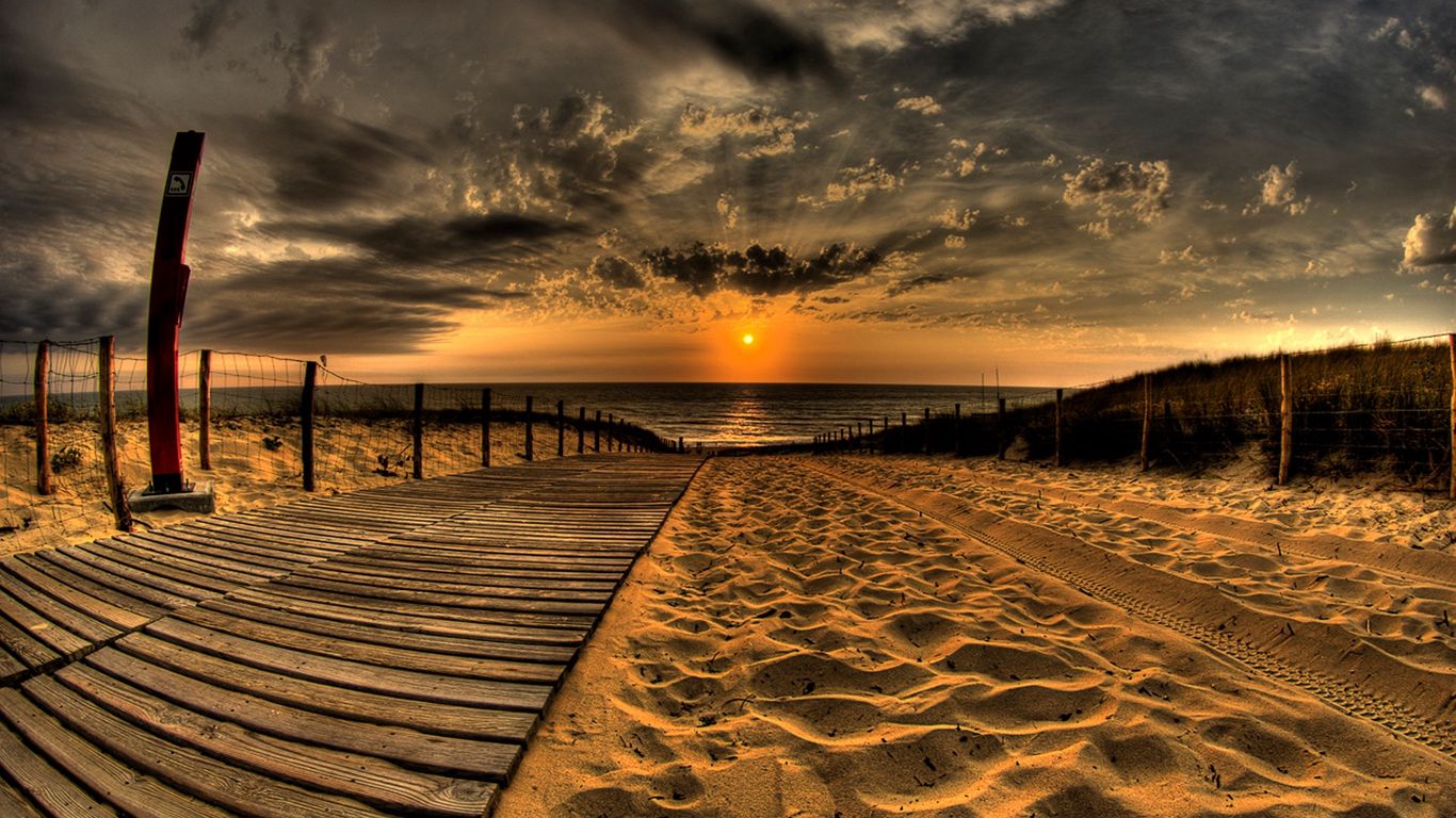 Download wallpaper 1366x768 beach, sand, road, traces, fence, sun, evening, sky, decline, clouds tablet, laptop HD background