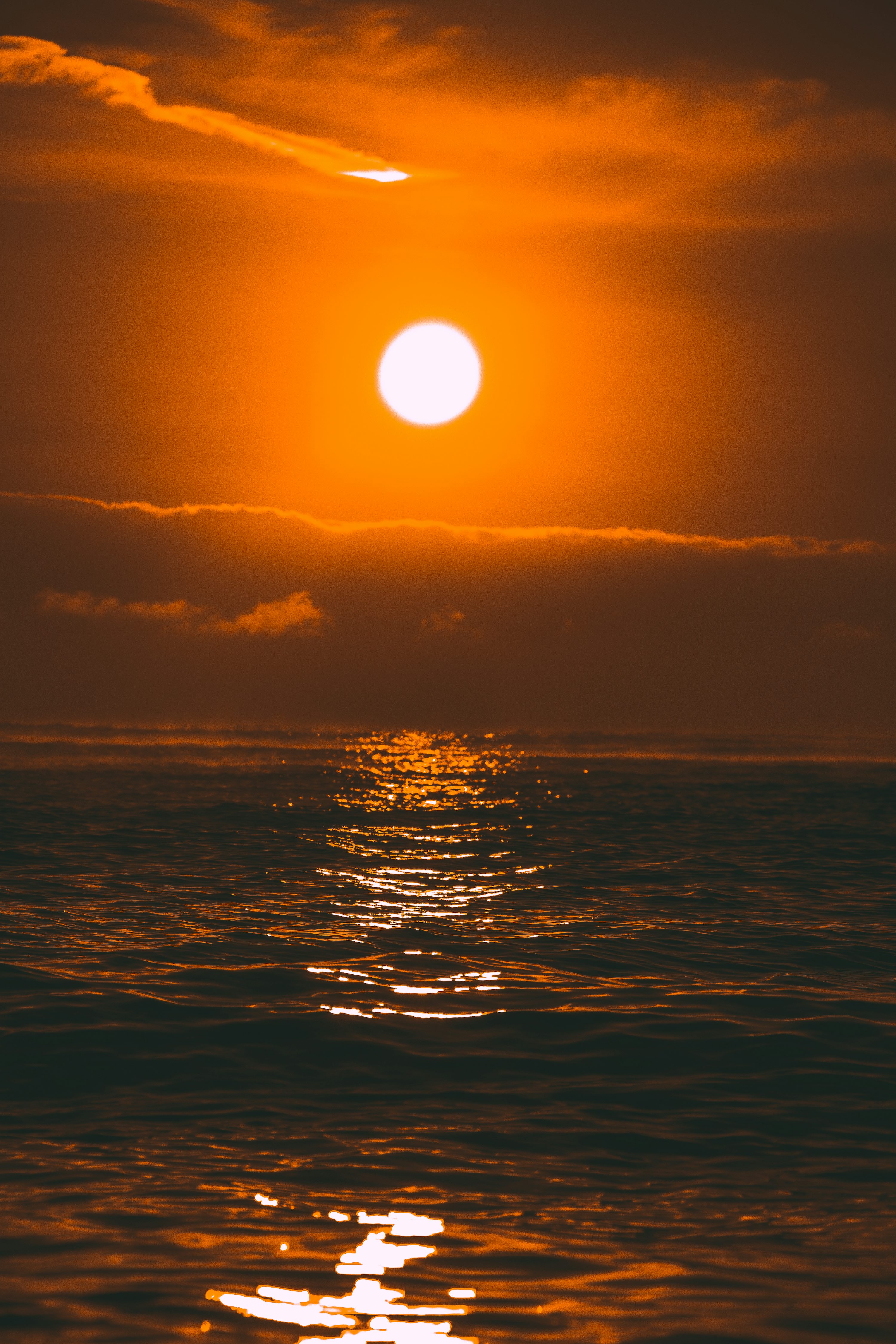 The sun is setting over the ocean on a cloudy day photo