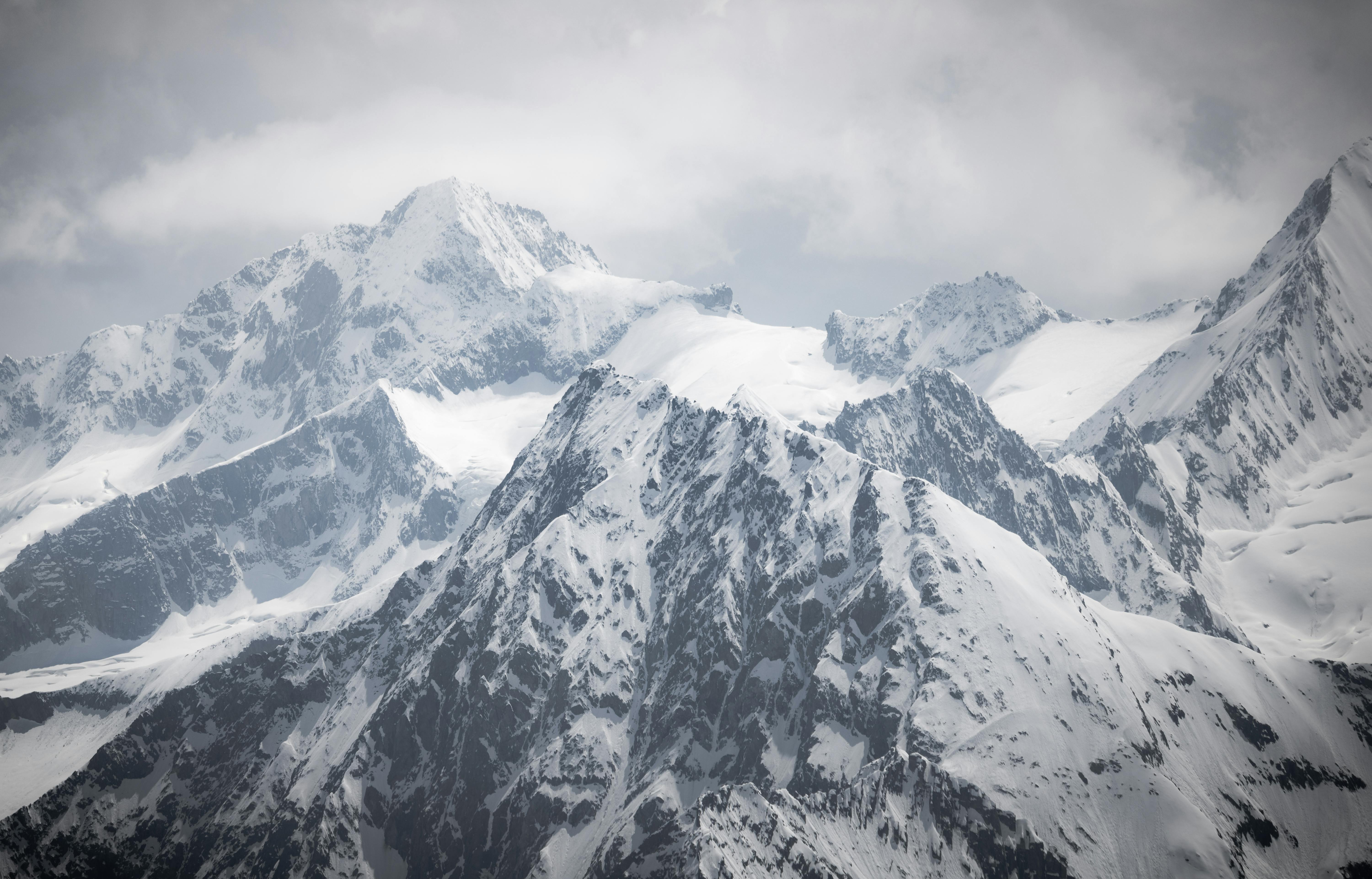 A photo of a snowy mountain range with clouds · Free