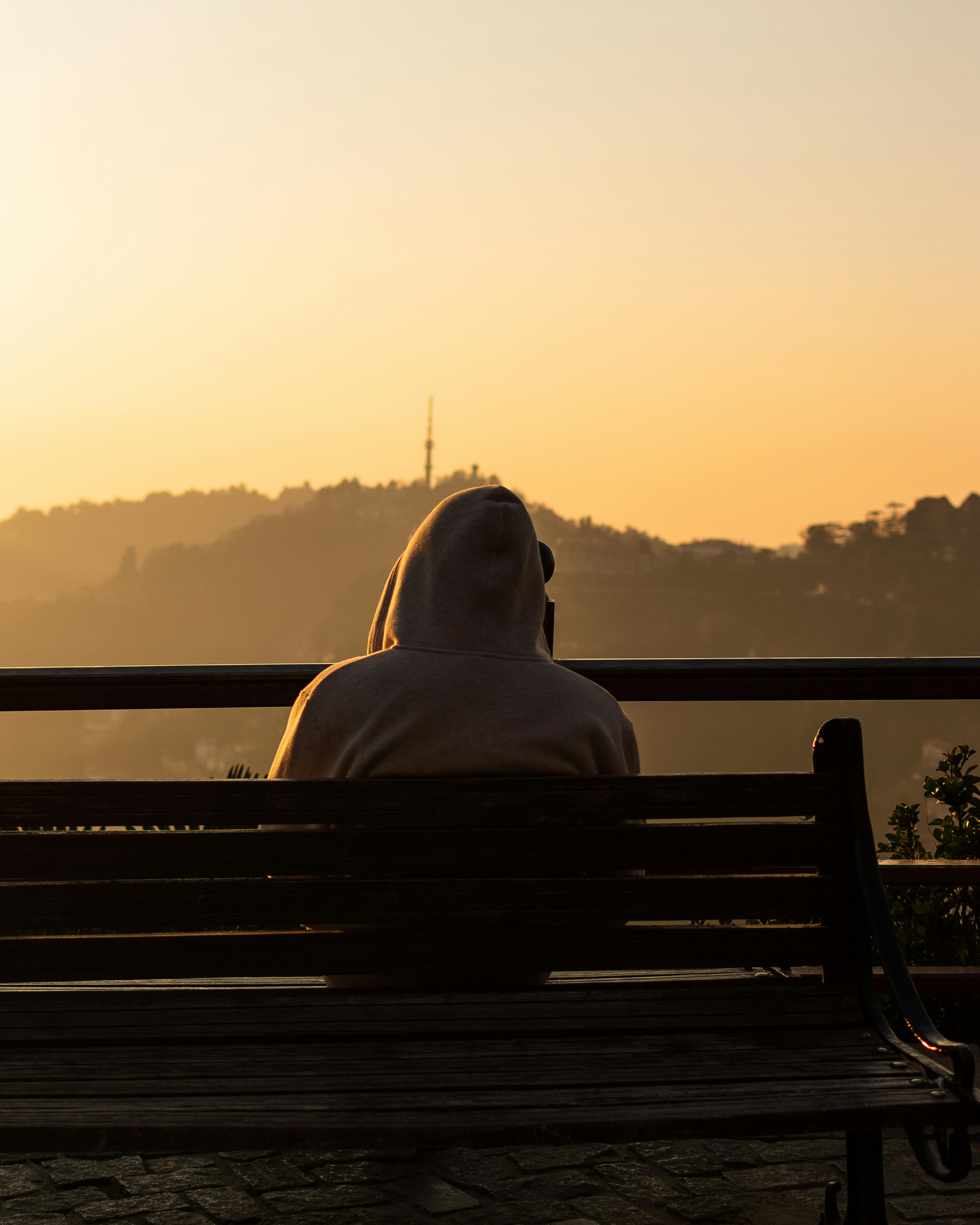 Man in Hoodie Sitting on Bench at Sunset · Free