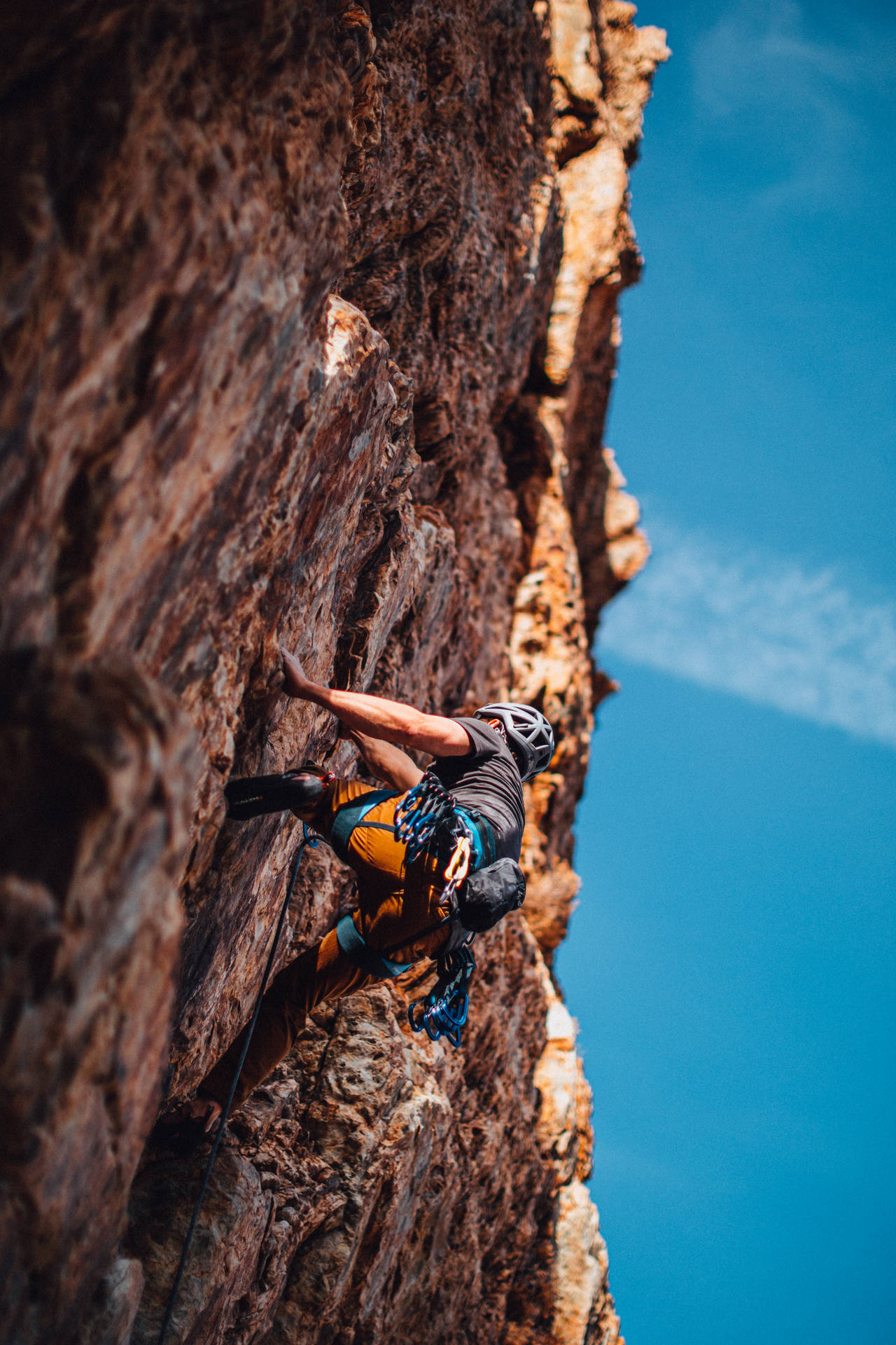 Download Man Rock Climbing Under A Blue Sky Wallpaper