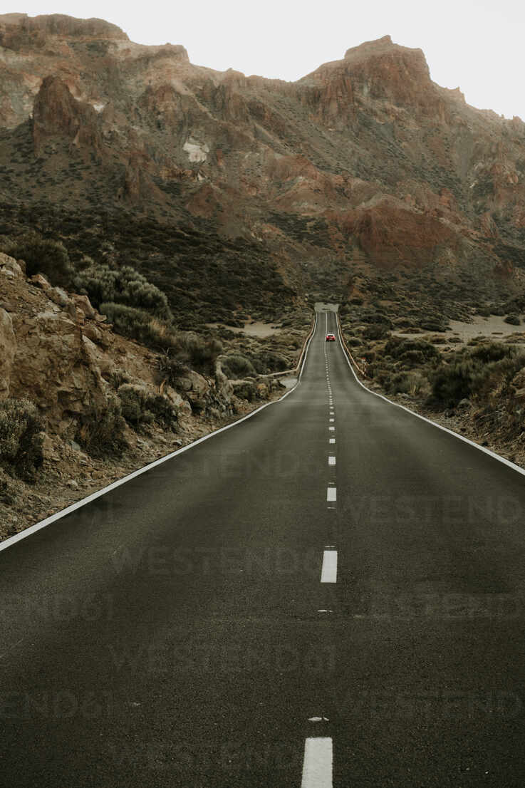 Perspective view to asphalt road in dry land leading to mountains