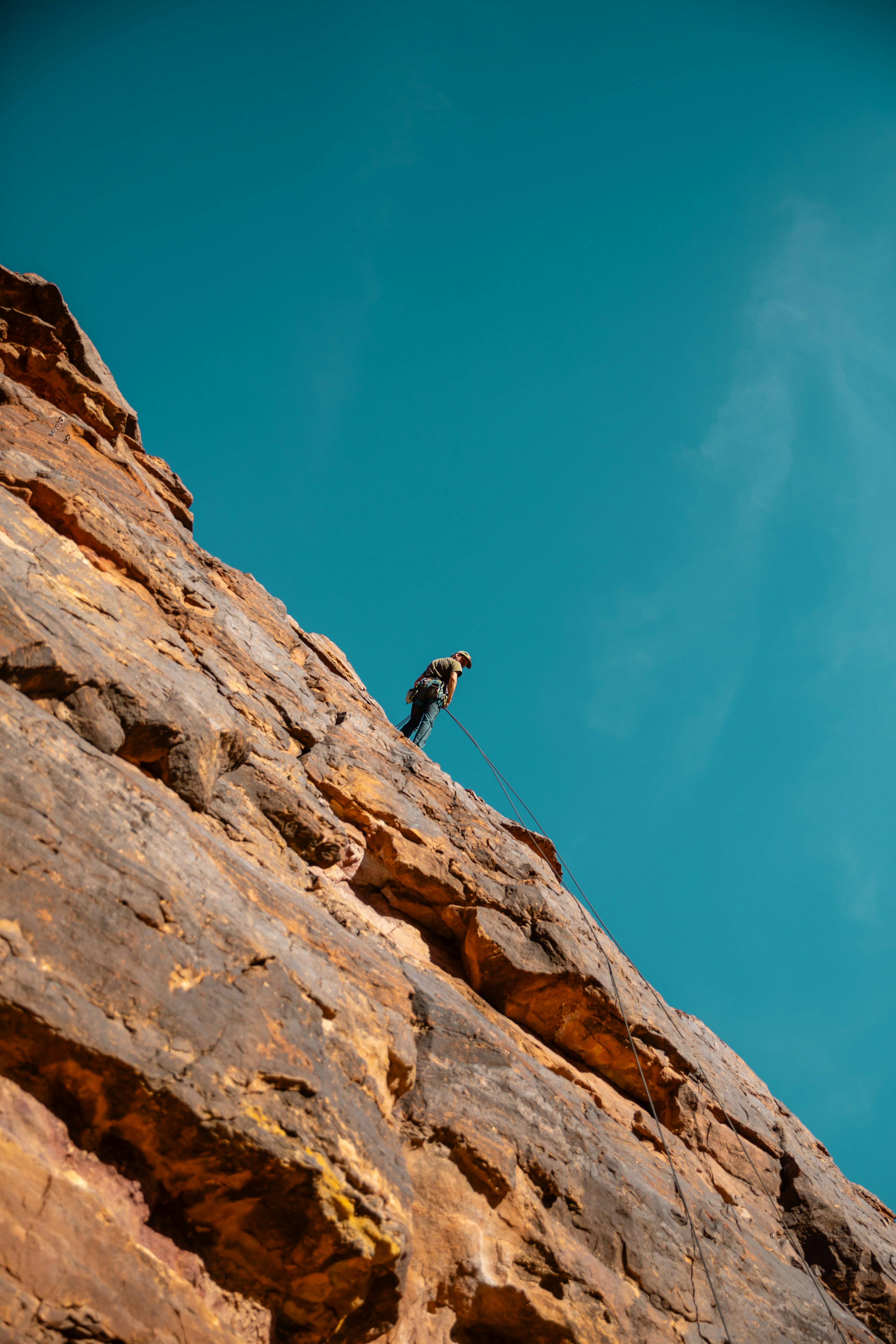 A climber ascends a steep and rocky cliff. photo