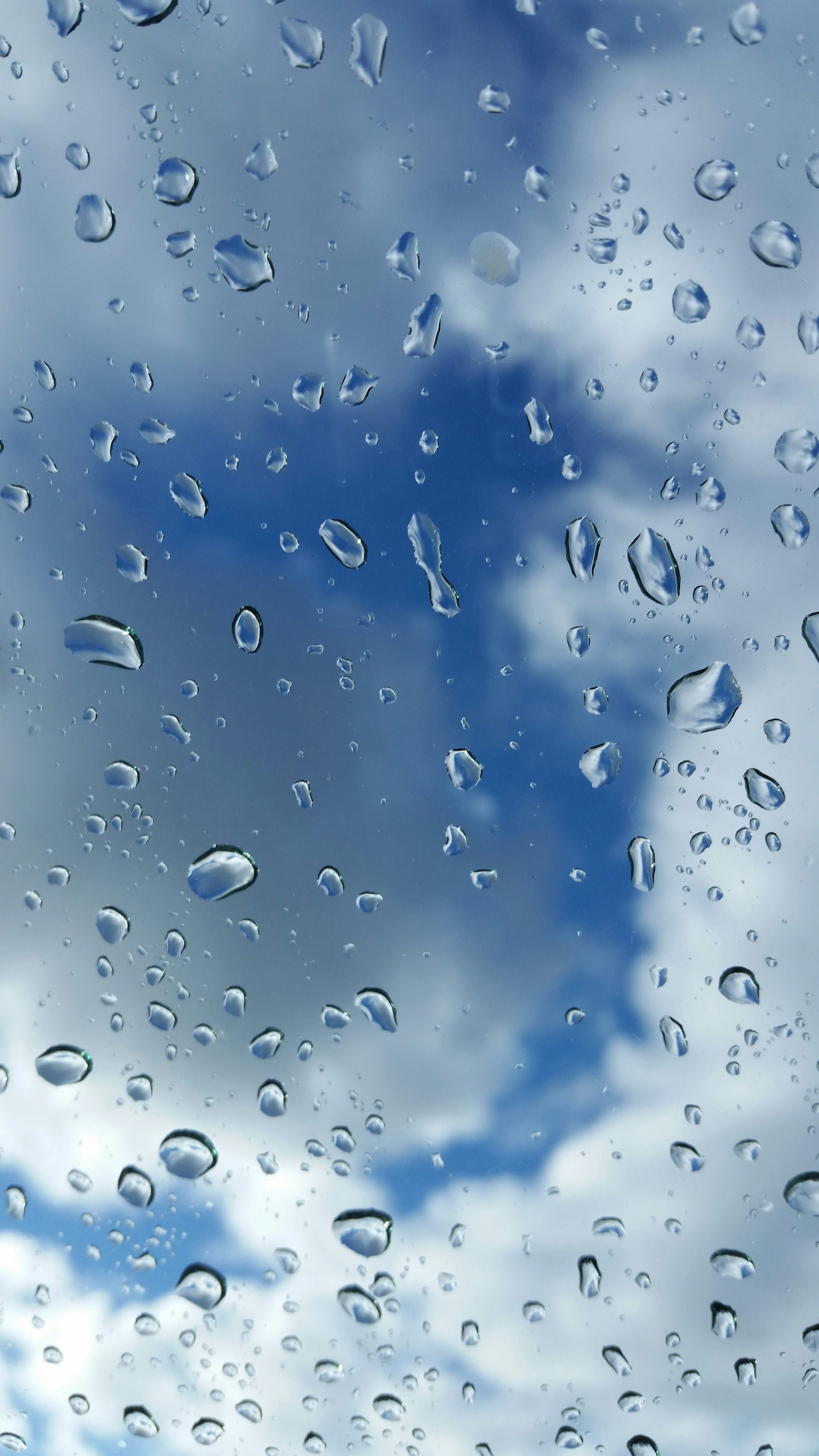 Rain drops on a window with a blue sky in the background photo