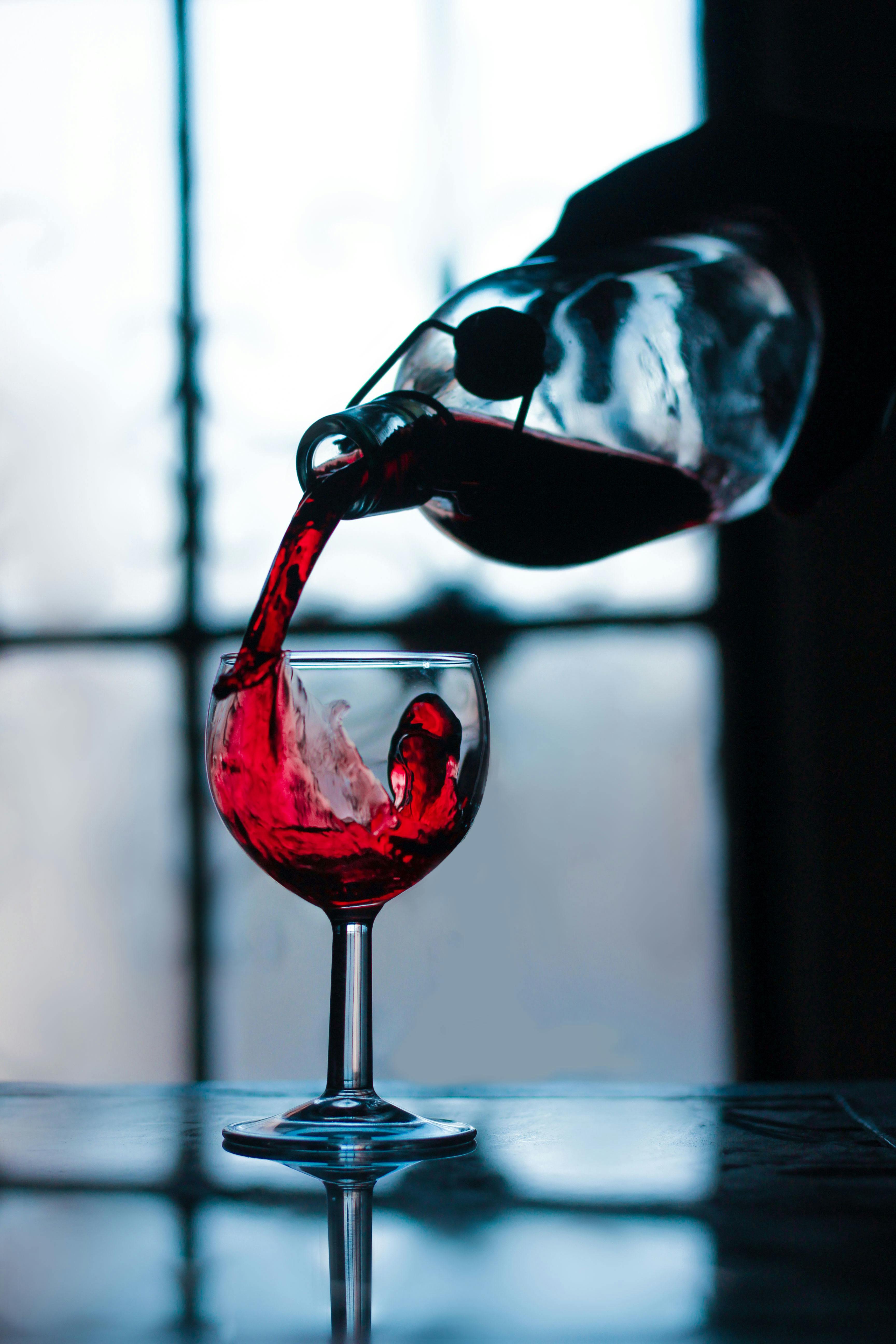 A Close Up Shot Of A Person Pouring Wine In A Glass · Free
