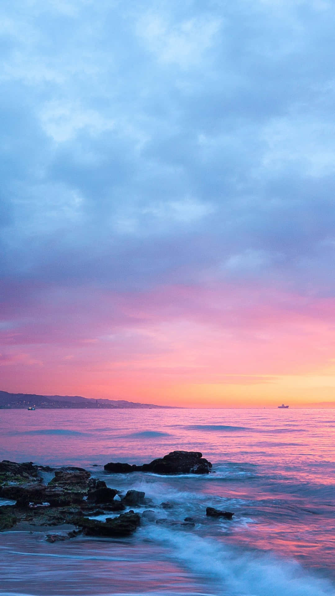 Download Pink Beach Sunset With Waves Hitting Rocks Wallpaper