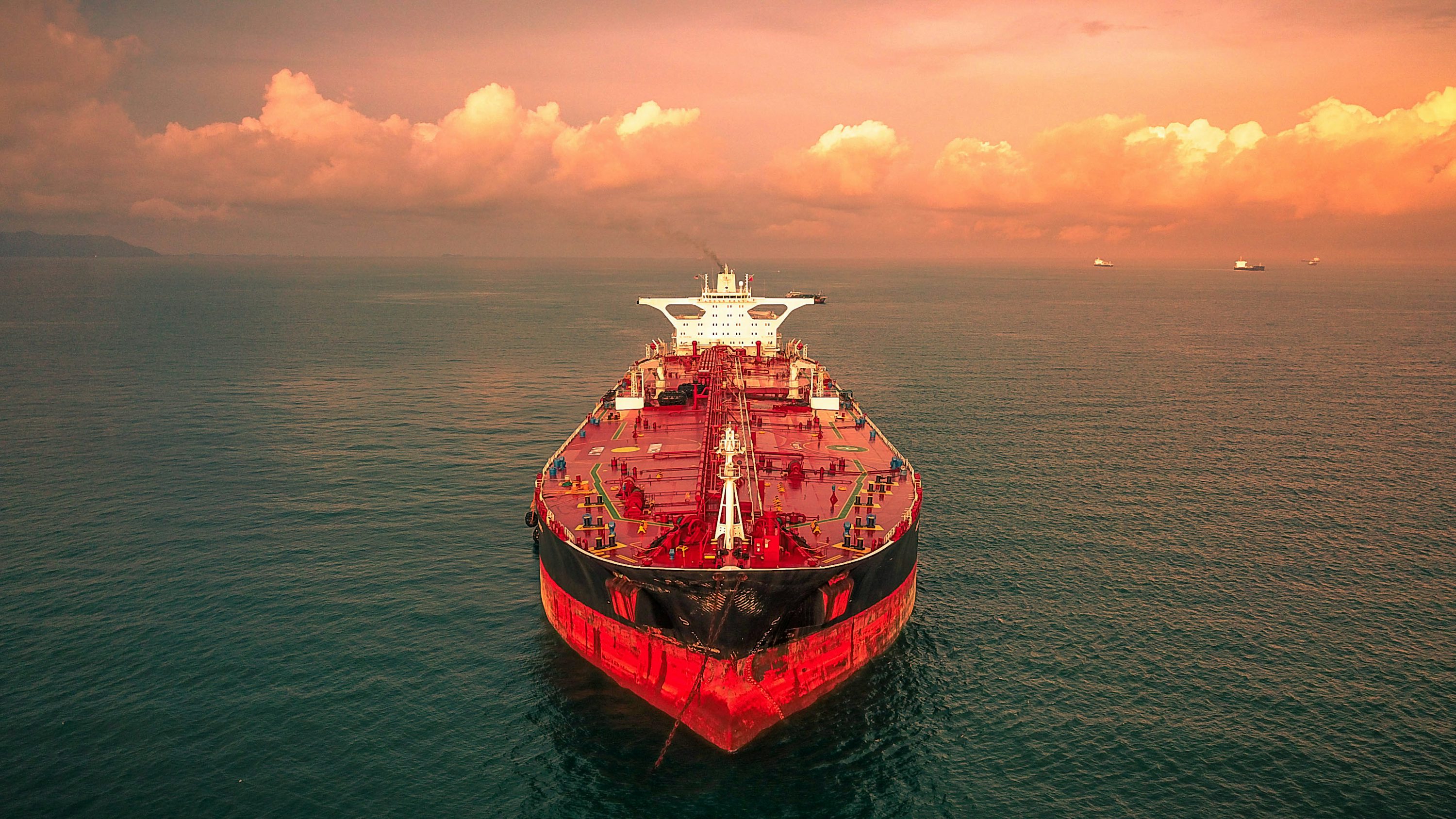 Red and white ship on sea under cloudy sky during daytime photo