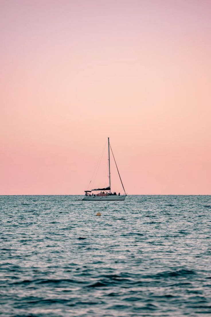 Sailing boat wallpaper during the sunset in the blue ocean with a beautiful aesthetic pink sky