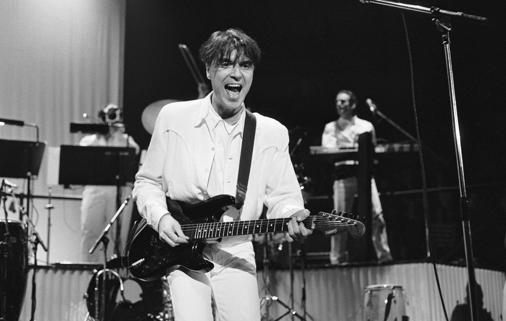 Download David Byrne Guitar Performance Photography Wallpaper