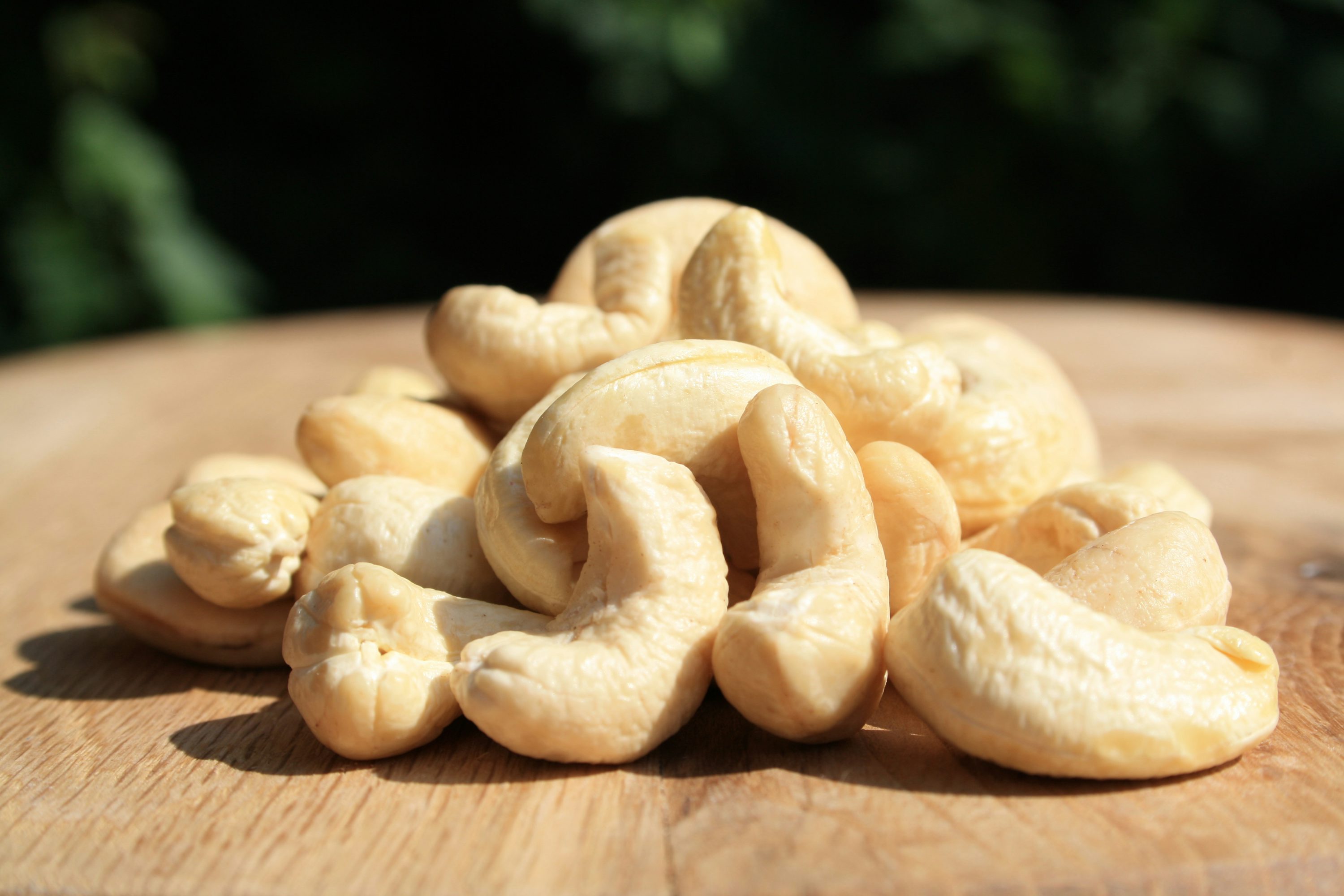 A pile of cashews sitting on top of a wooden table photo