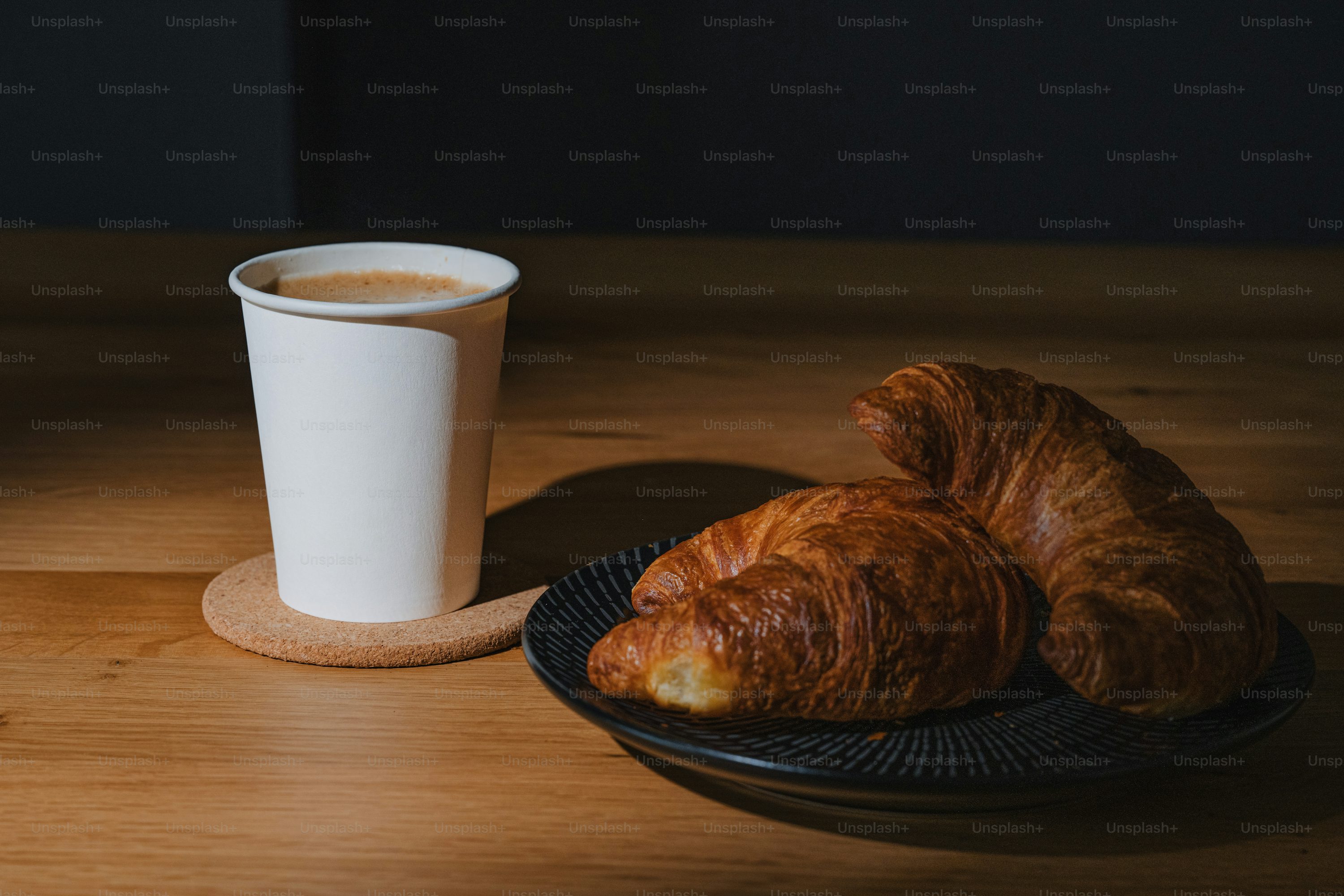Two croissants on a plate next to a cup of coffee photo