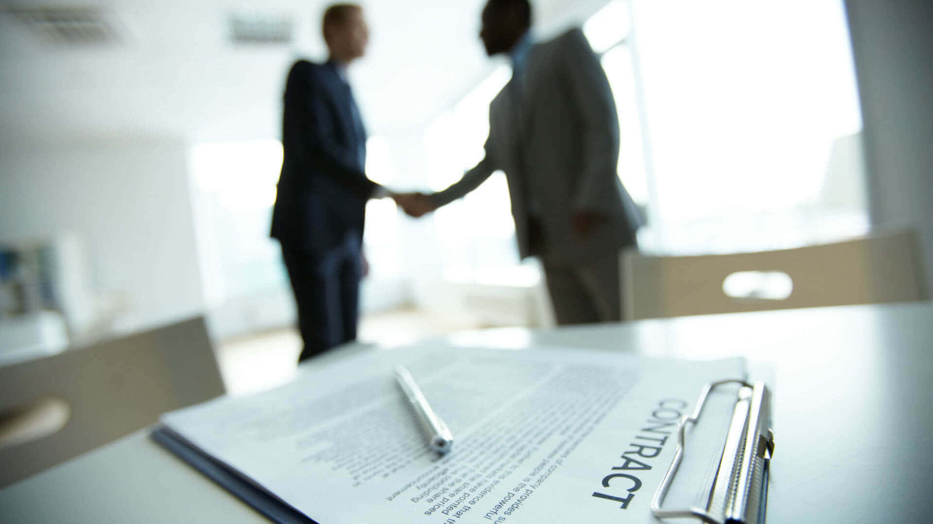 Download Two Businessmen Finalizing Contract Agreement Wallpaper