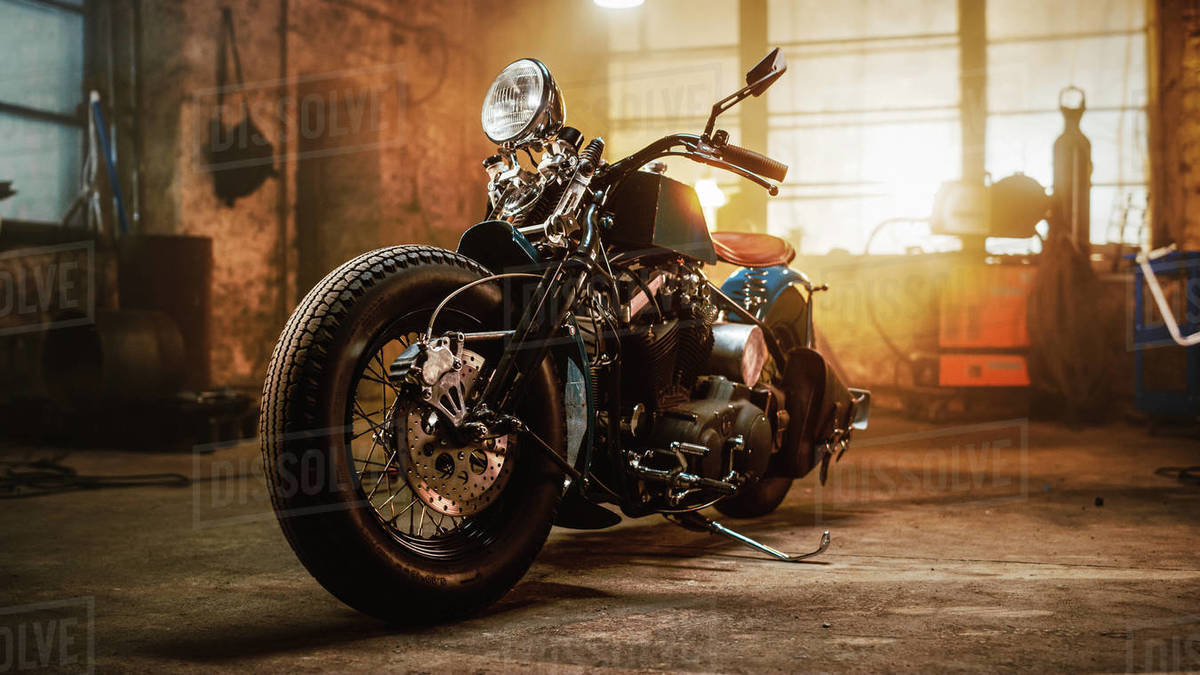 Custom Bobber Motorbike Standing in an Authentic Creative Workshop. Vintage Style Motorcycle Under Warm Lamp Light in a Garage.-free