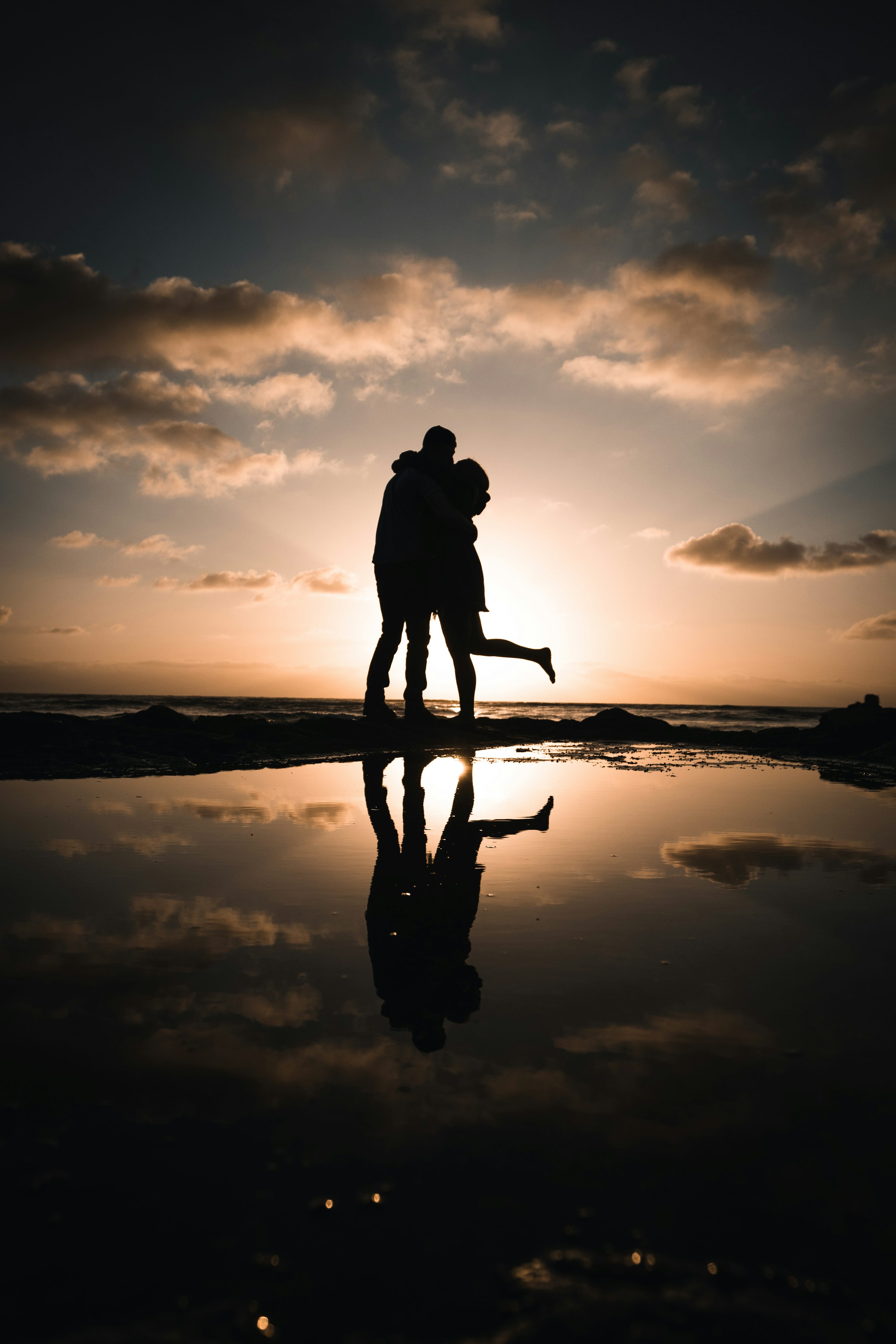 Silhouette of man and woman standing on seashore during sunset photo