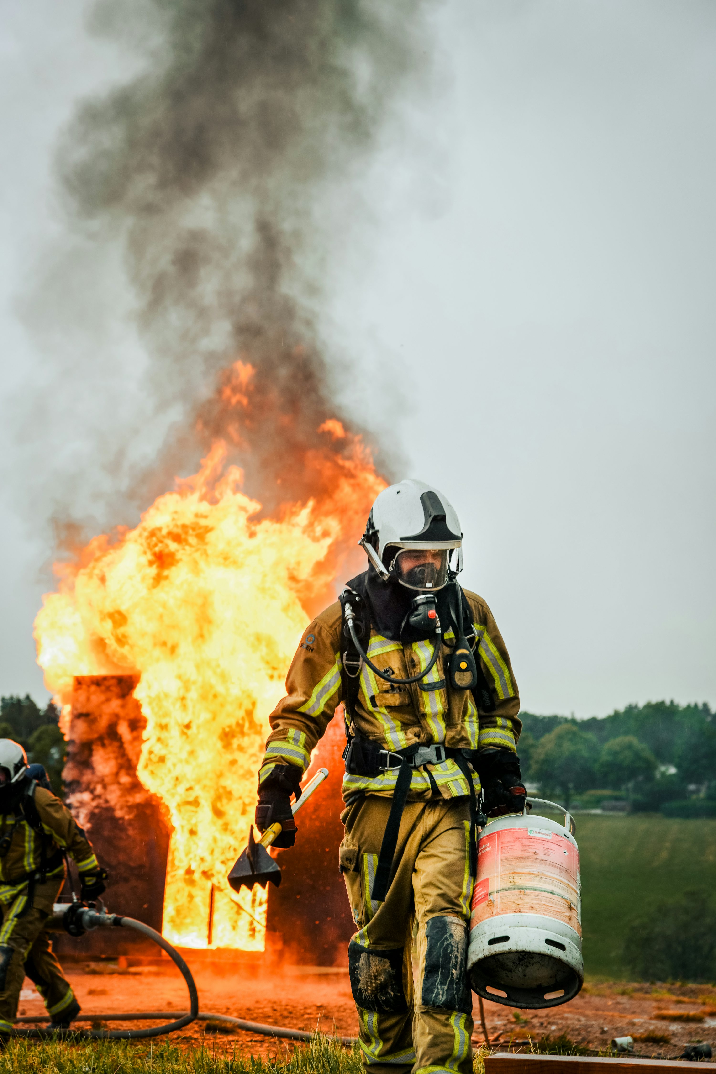 Due vigili del fuoco davanti a un grande incendio foto