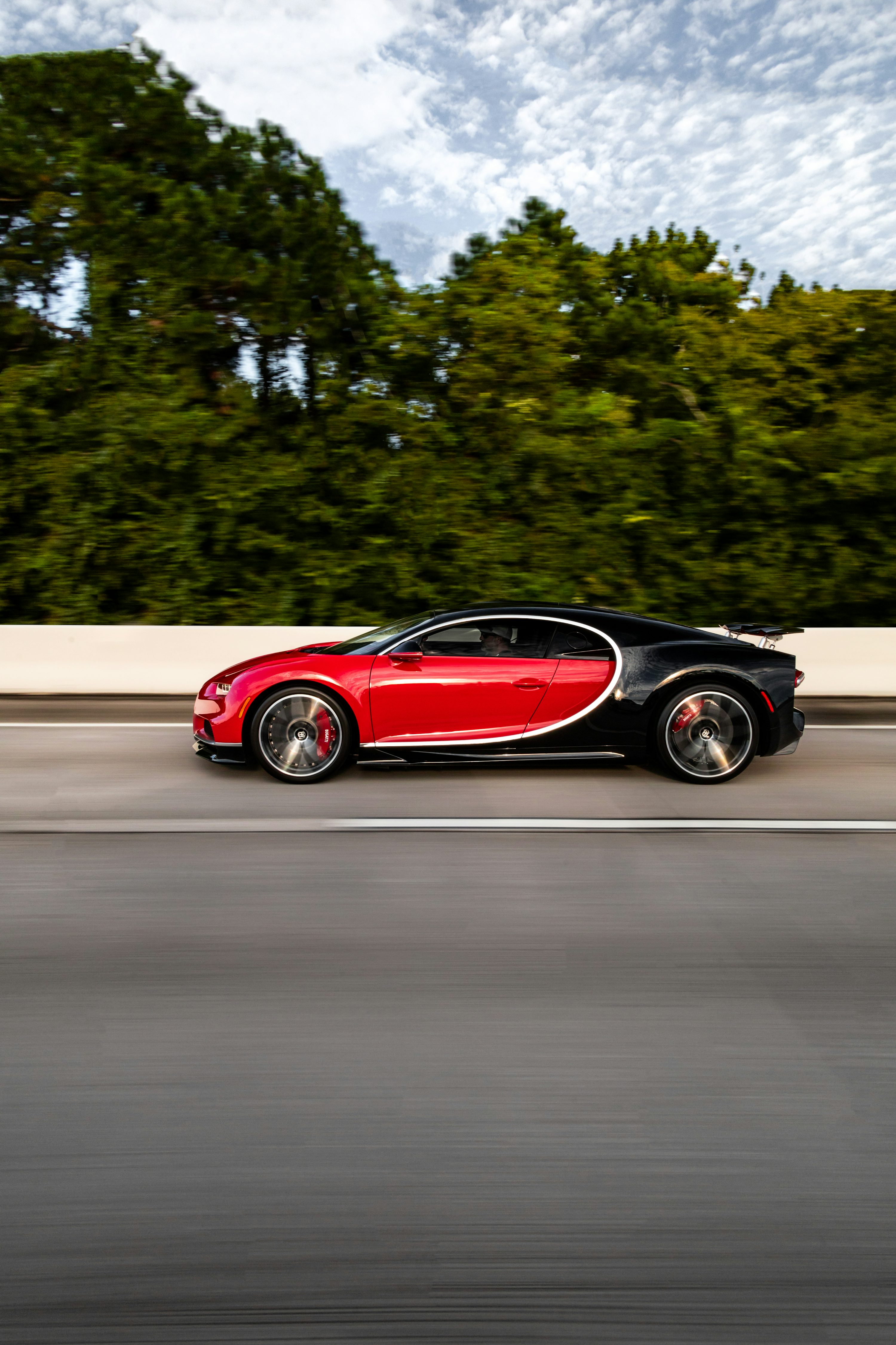 A red and black bugatti driving down the road photo