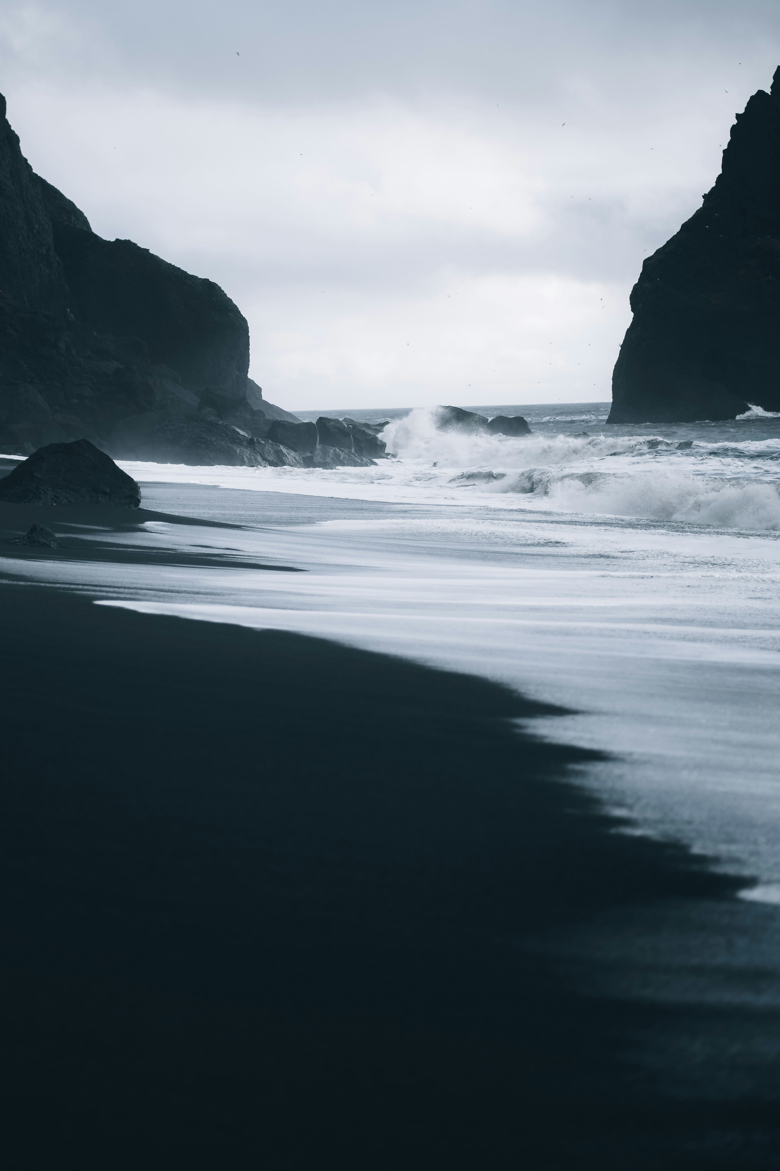 A black sand beach with waves coming in to shore photo